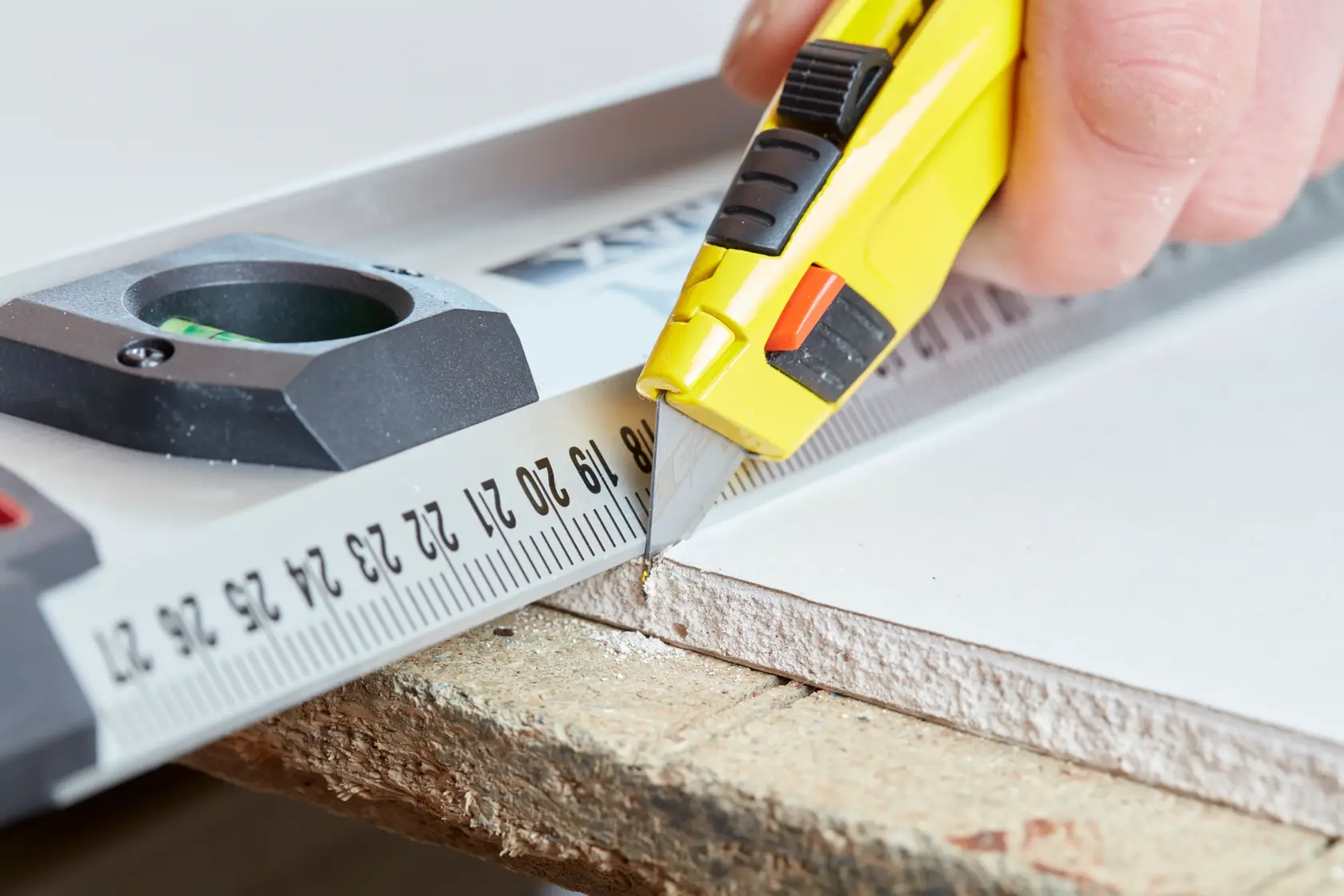 STANLEY 0-11-800 utility knife cutting along a ruler on drywall, close-up photography.