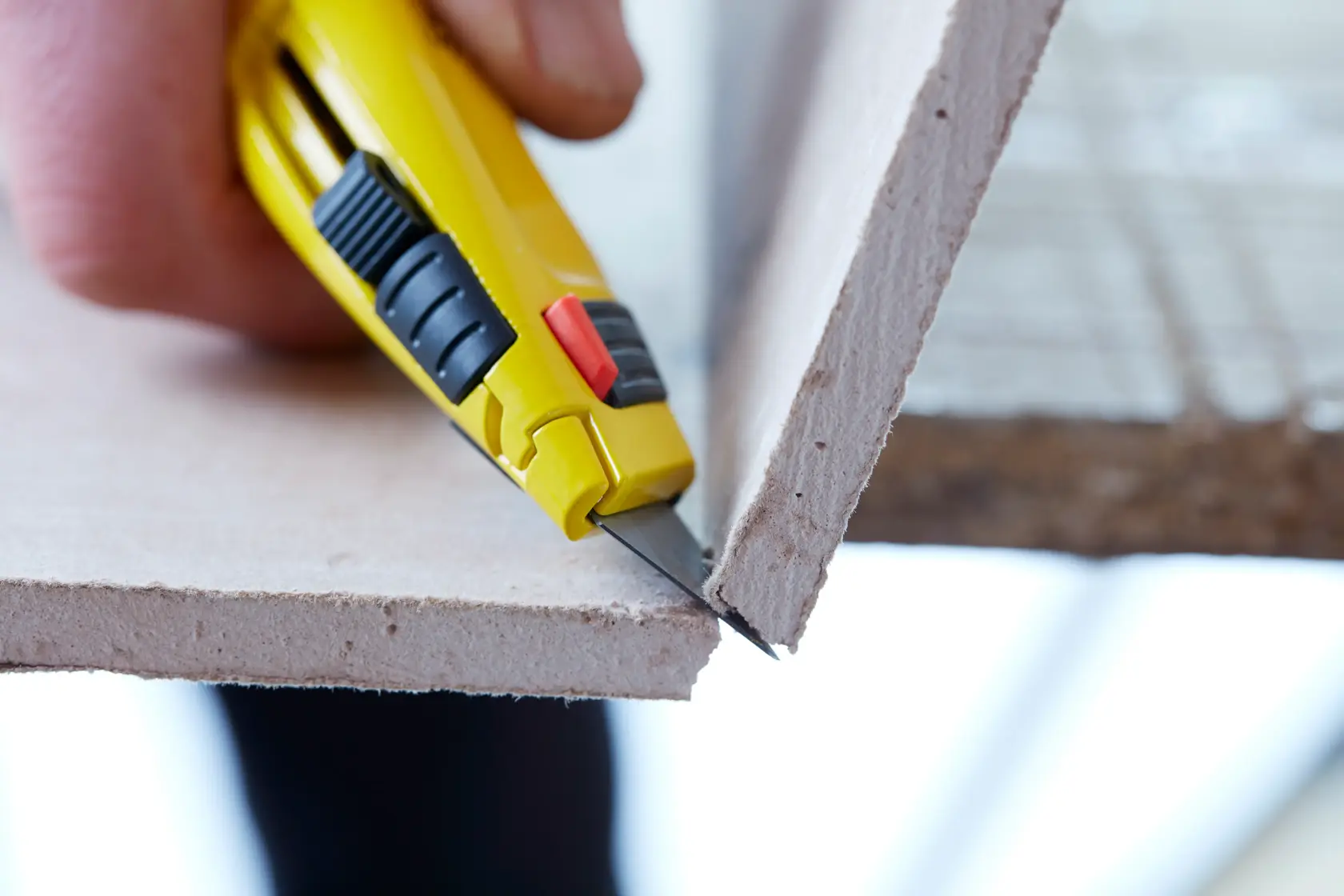 STANLEY 0-11-800 utility knife cutting drywall, close-up view of blade and yellow handle.