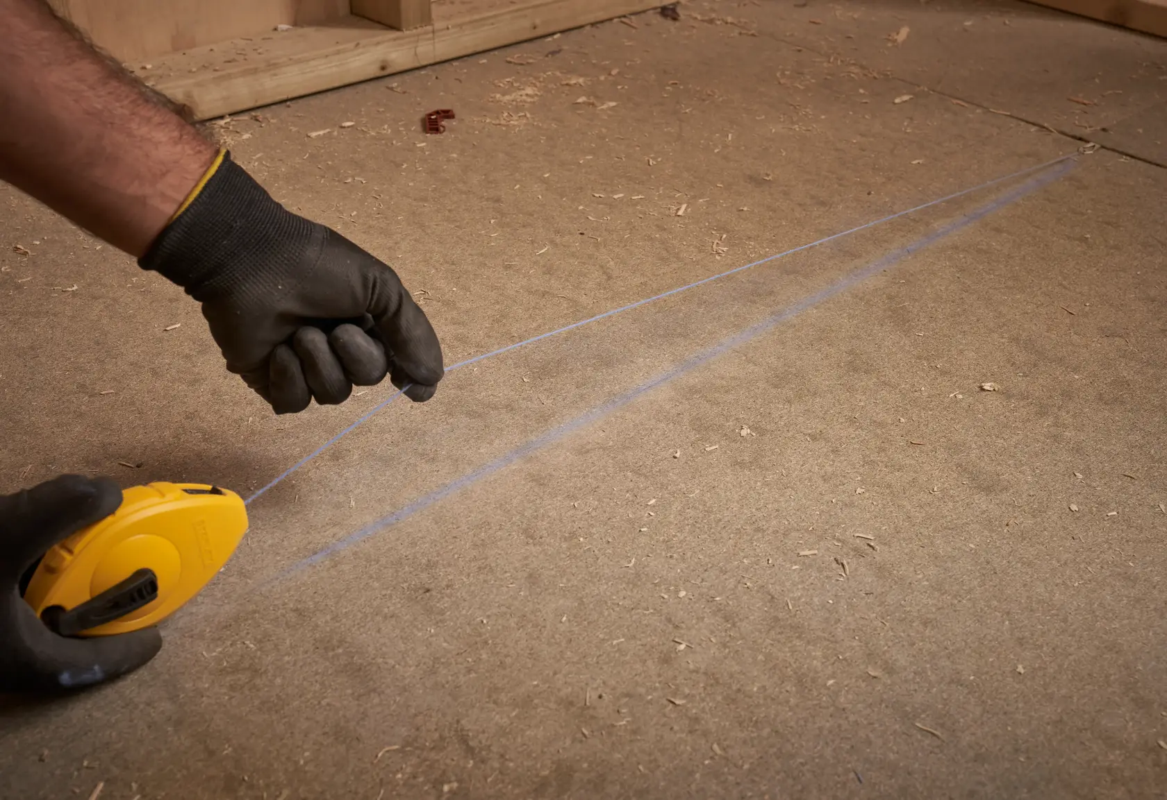 STANLEY 0-47-440 chalk line reel in use, yellow casing, line marking on wooden floor, close-up.