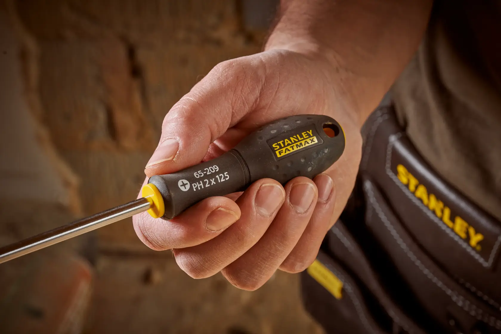 Photo of STANLEY 0-65-209 screwdriver with black and yellow handle, held in hand, close-up view.