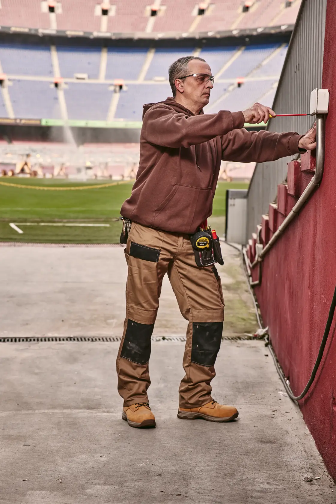 STANLEY 0-65-443 screwdriver used by a worker adjusting an outdoor electrical box near a stadium field.