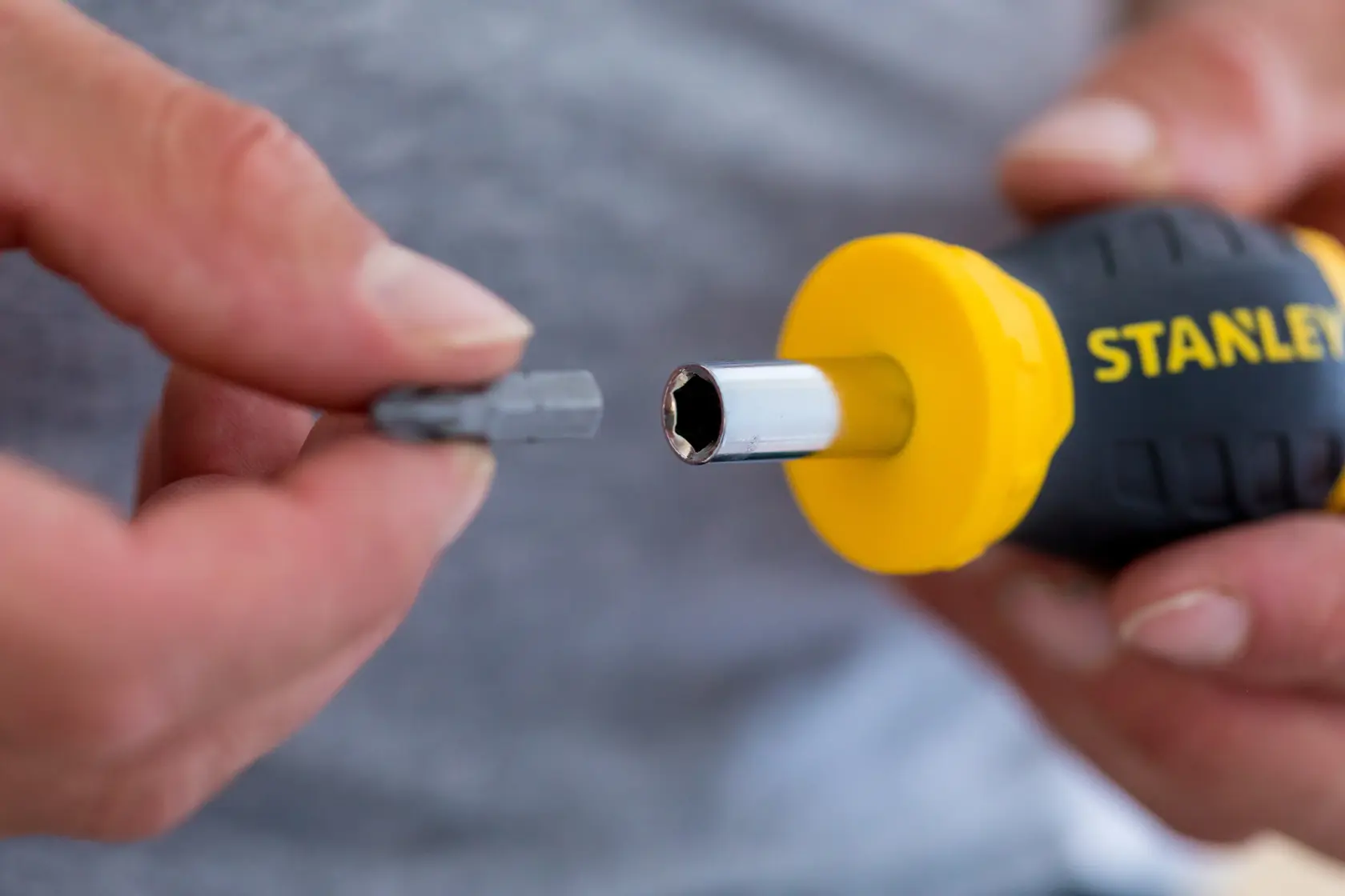 STANLEY 0-66-357 screwdriver handle with yellow accent and interchangeable bit held in hand, close-up.