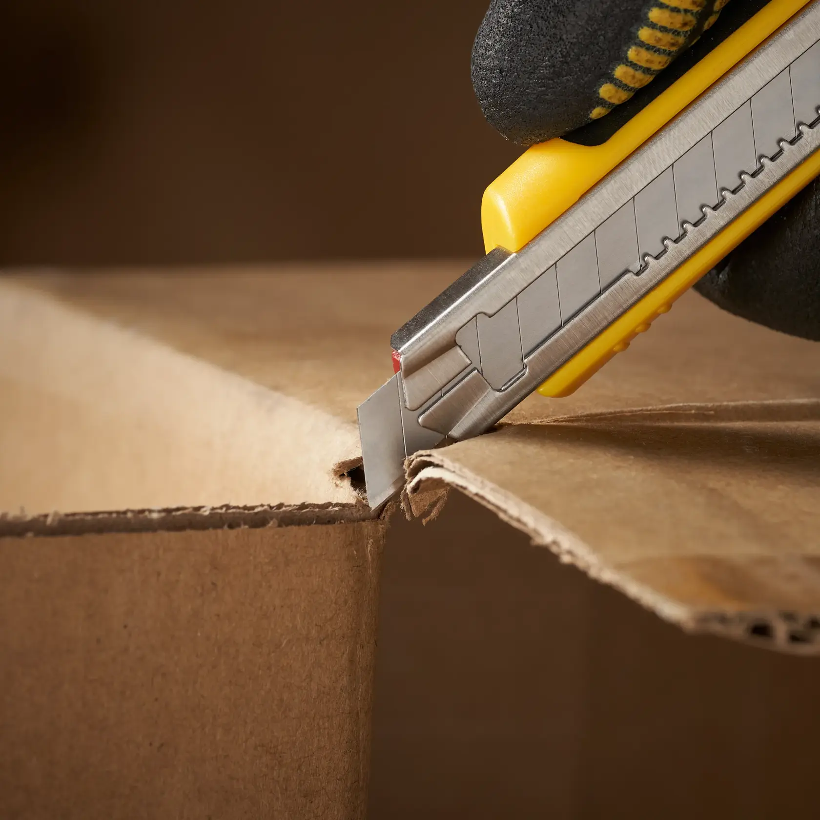 STANLEY 1-11-300 utility knife cutting cardboard, close-up side view.