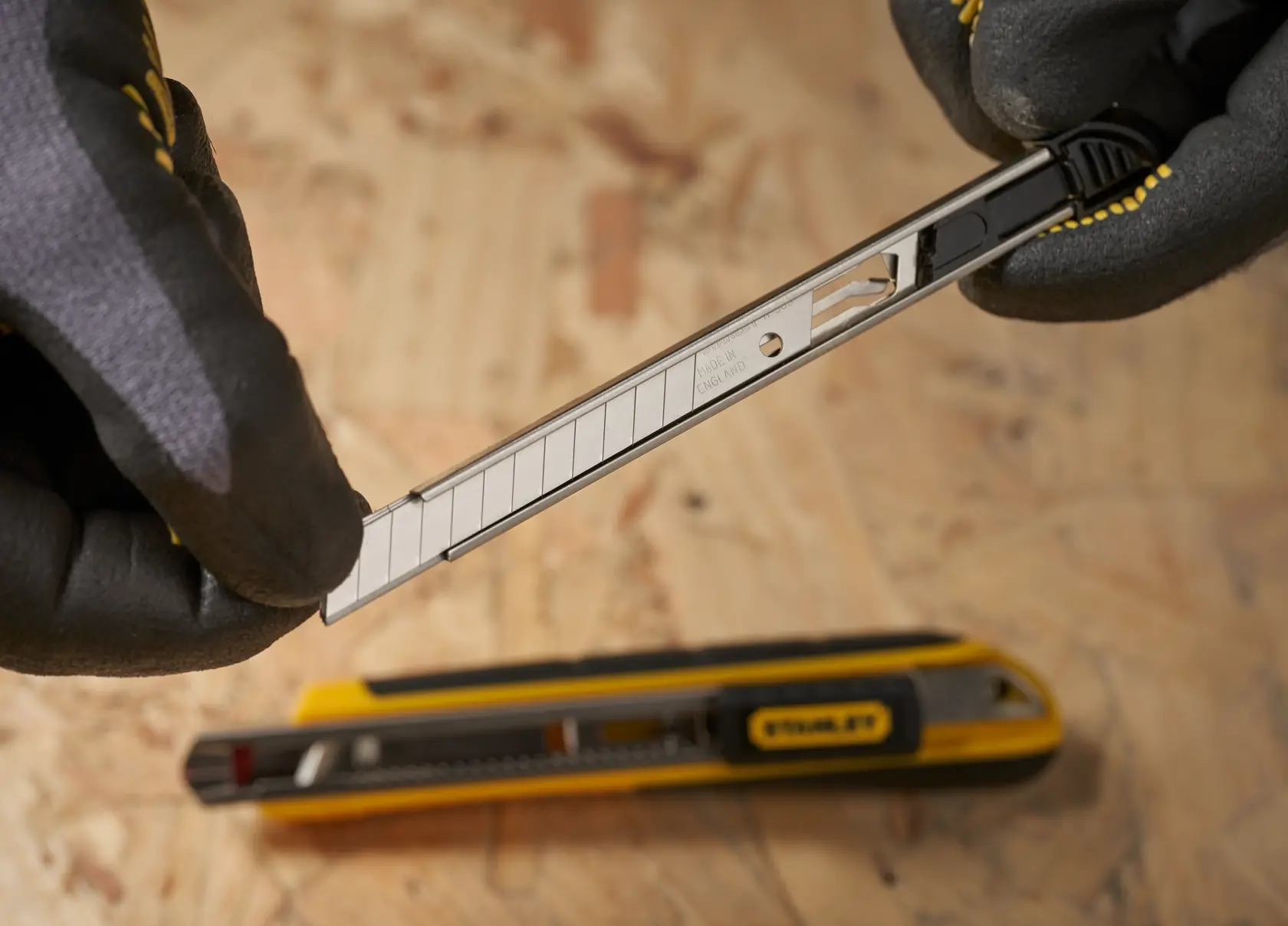 STANLEY 1-11-300 snap-off blade utility knife in use, close-up photography on plywood surface.