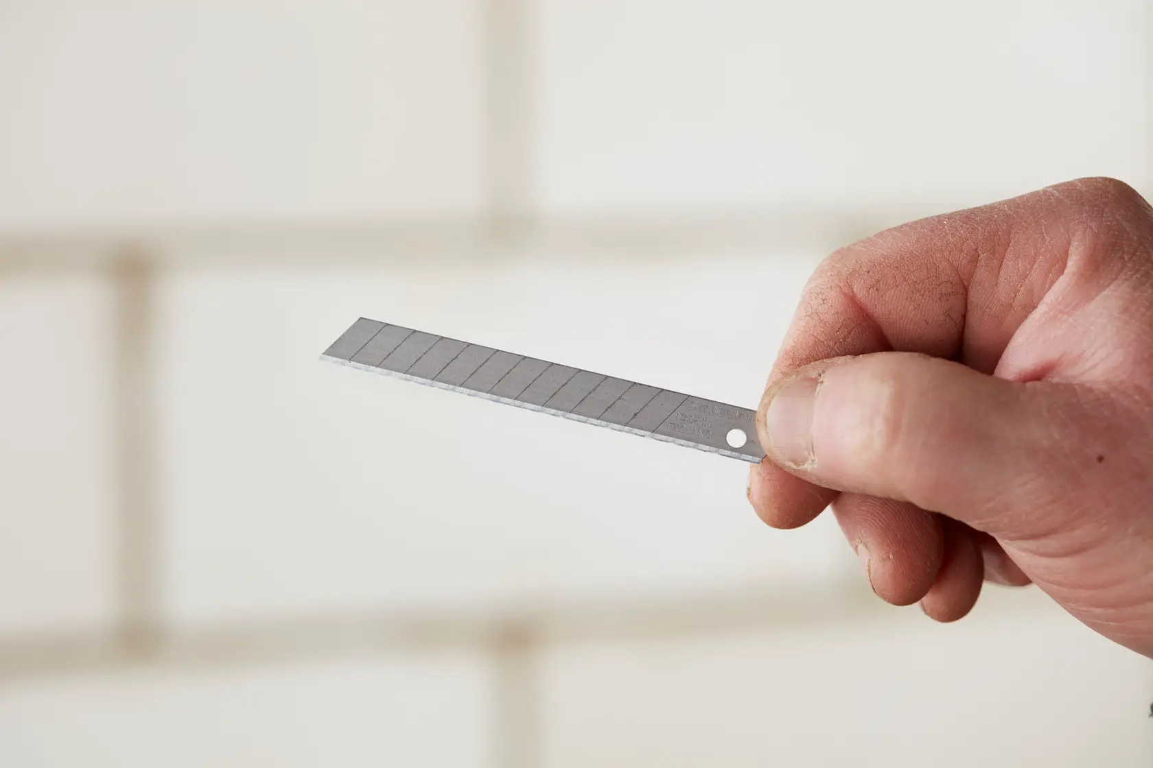 STANLEY 1-11-300 snap-off utility blade held in hand, close-up, showing segmented metal design.