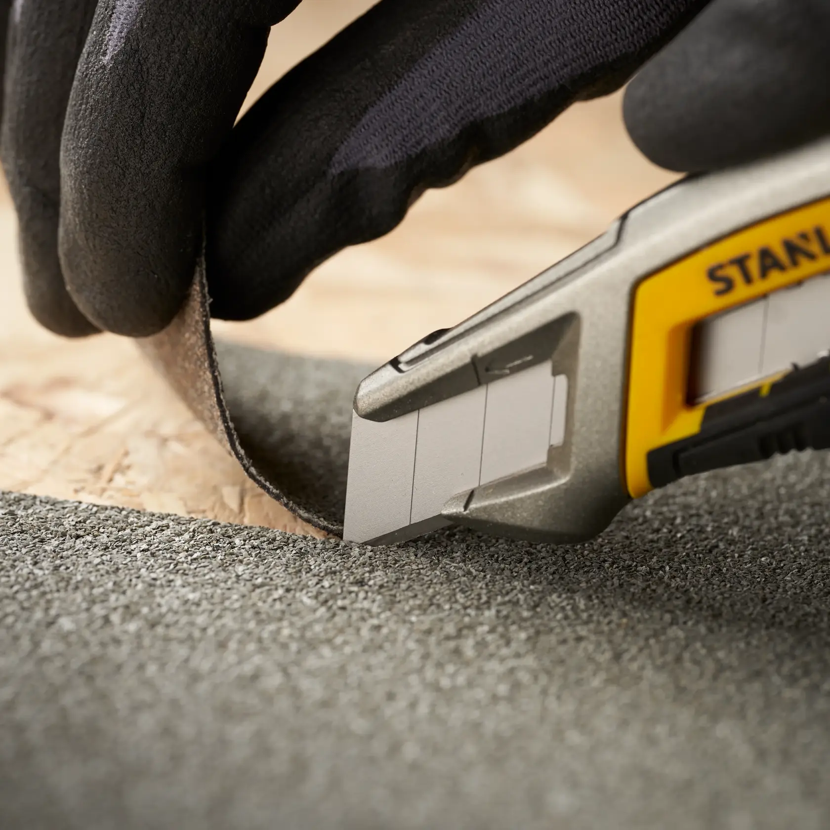 STANLEY 1-11-301 utility knife cutting textured material, close-up photo with gloved hand.