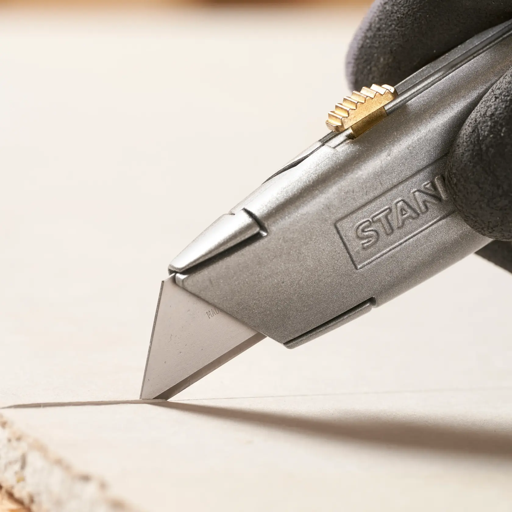 STANLEY 1-11-921 utility knife close-up cutting material, silver body with brass slider.