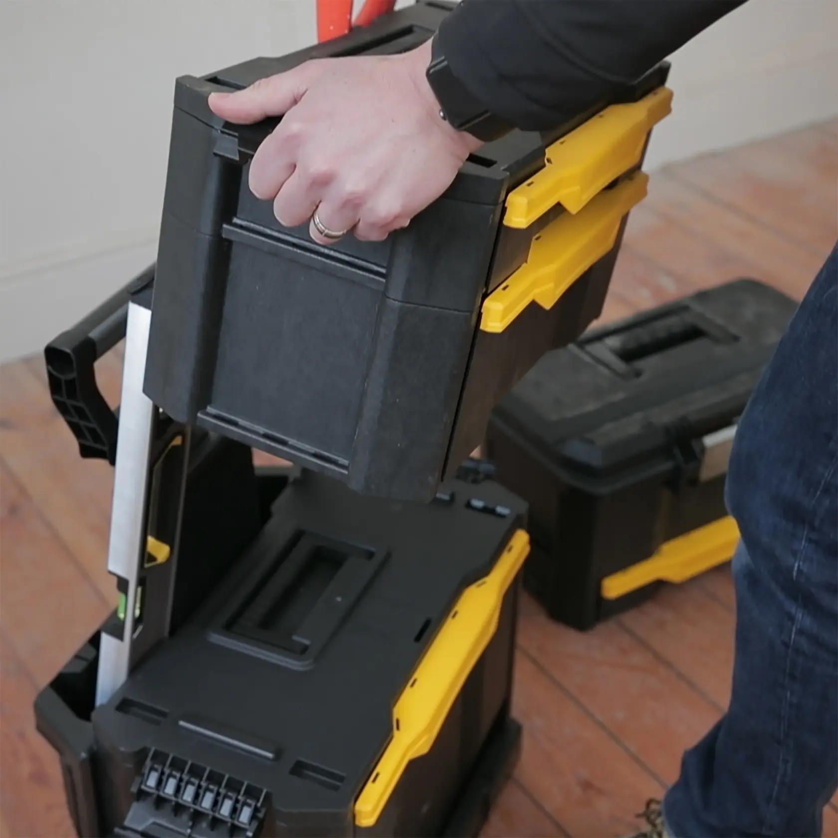 STANLEY 1-79-206 stackable black and yellow tool box being lifted by hand, photography close-up.