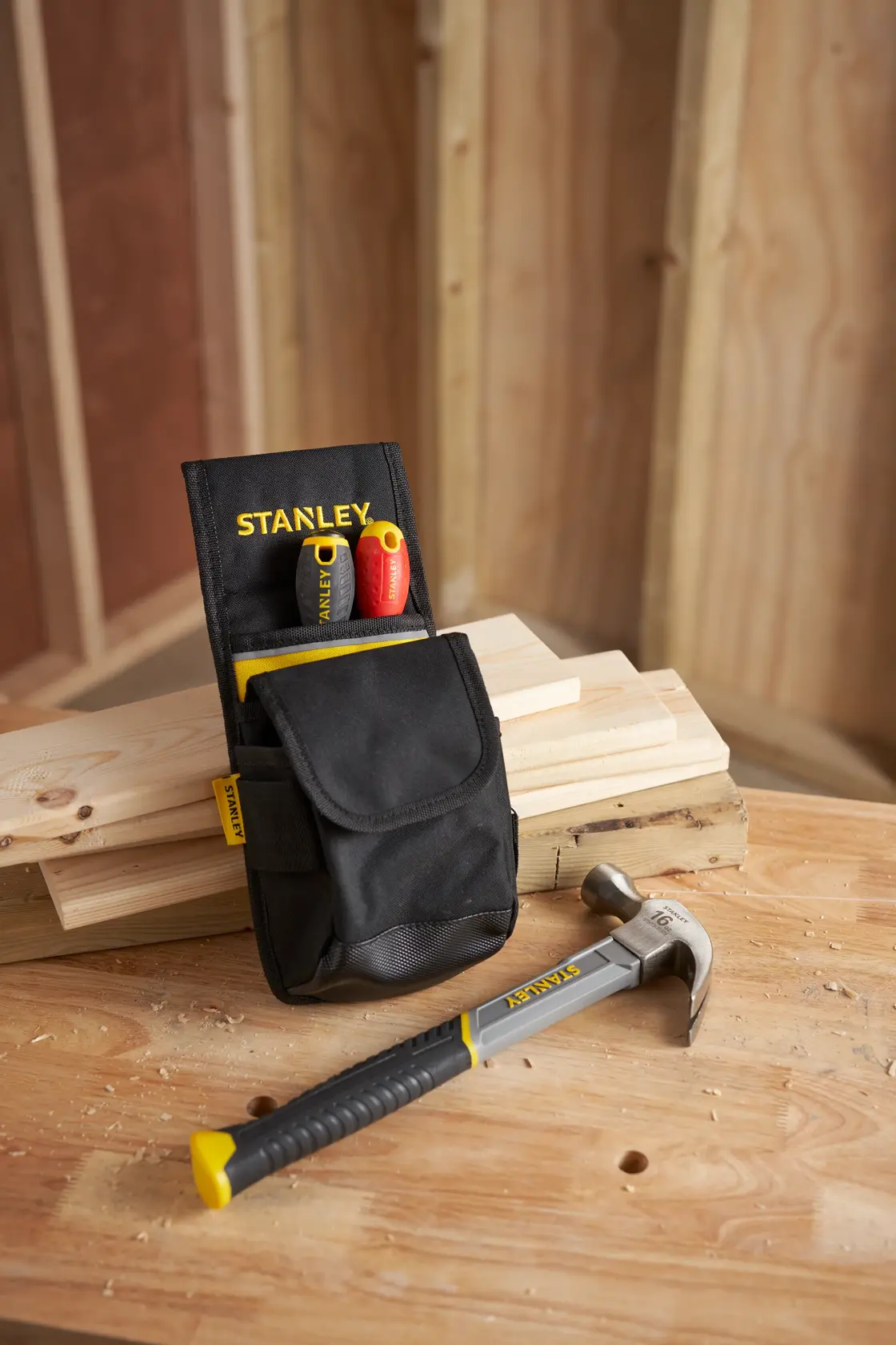 STANLEY 1-93-329 tool pouch with two screwdrivers and hammer on a wooden workbench in workshop.