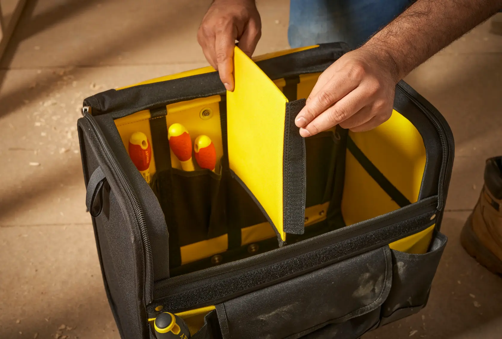STANLEY 1-97-515 tool bag with yellow interior divider, hand holding divider, front angle.