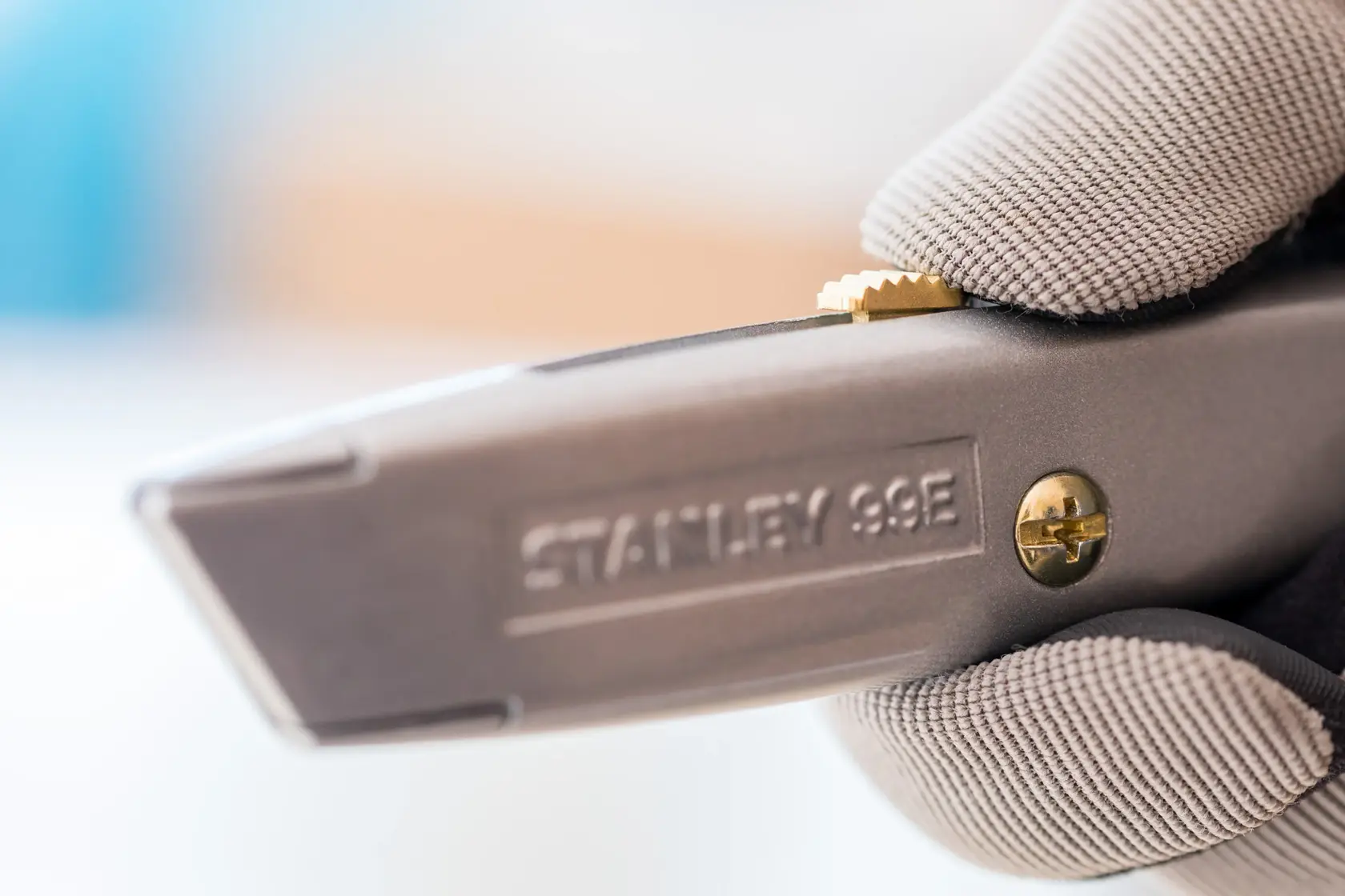 Close-up of STANLEY 2-10-099 utility knife in gloved hand, showing blade and brass screw.