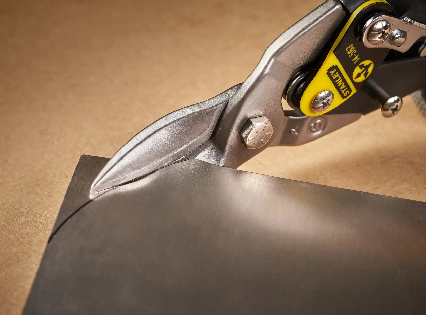 Photo of STANLEY 2-14-563 aviation snips cutting a sheet of metal, close-up view.
