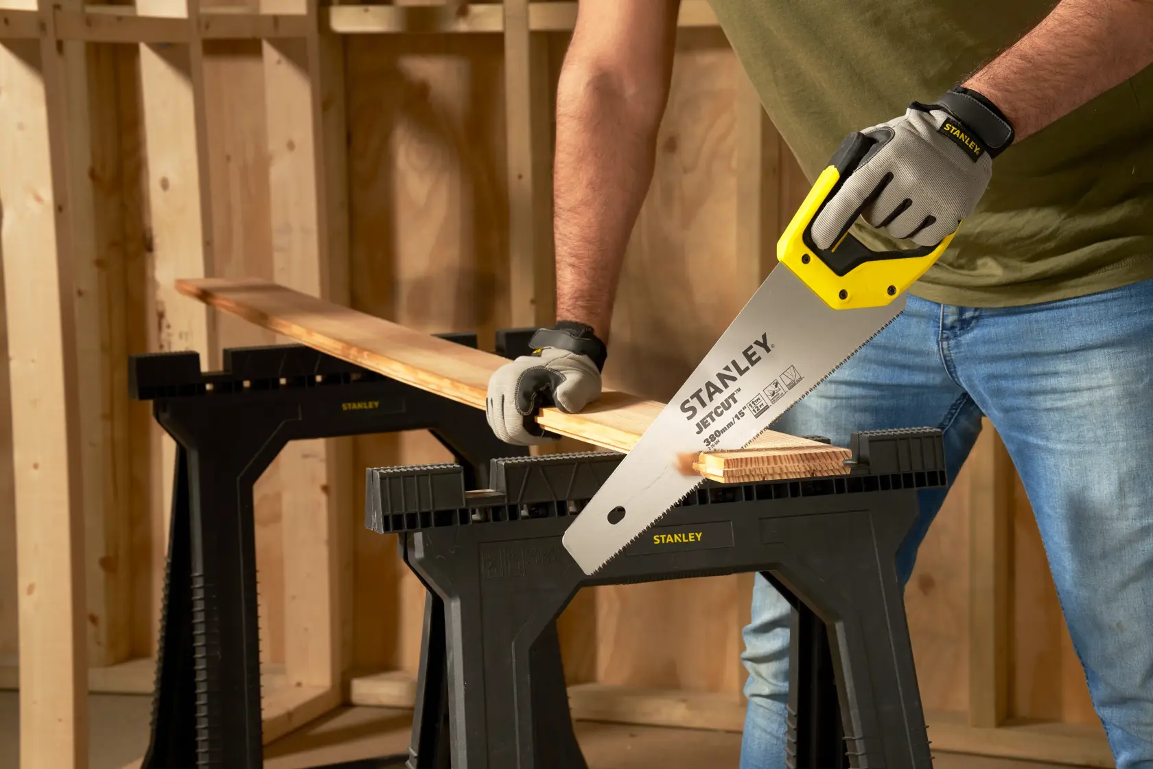 Stanley 2-15-594 hand saw used to cut wood on black Stanley sawhorses in workshop photography.