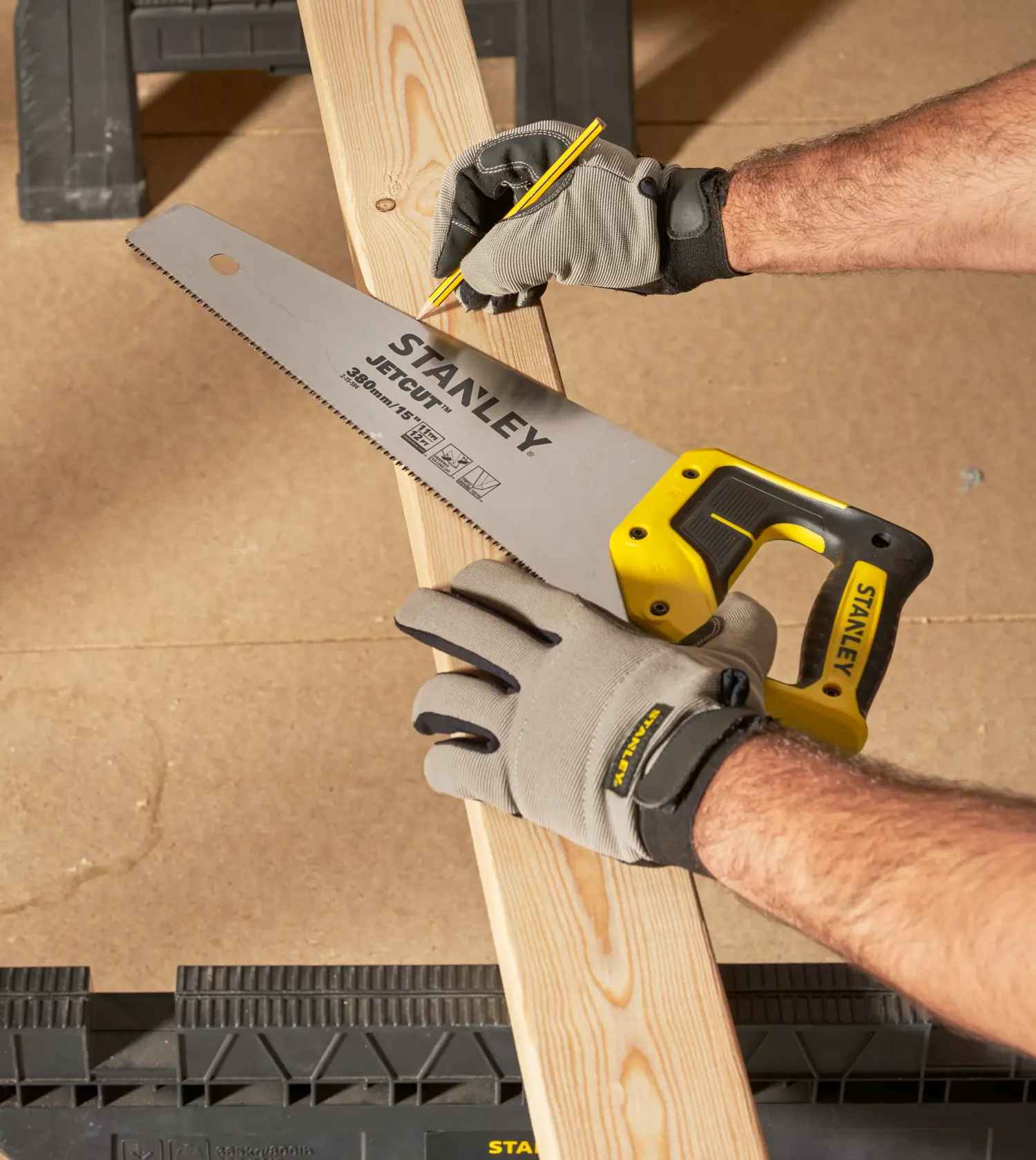 STANLEY 2-15-594 hand saw with yellow handle held on wood plank, close-up angle.