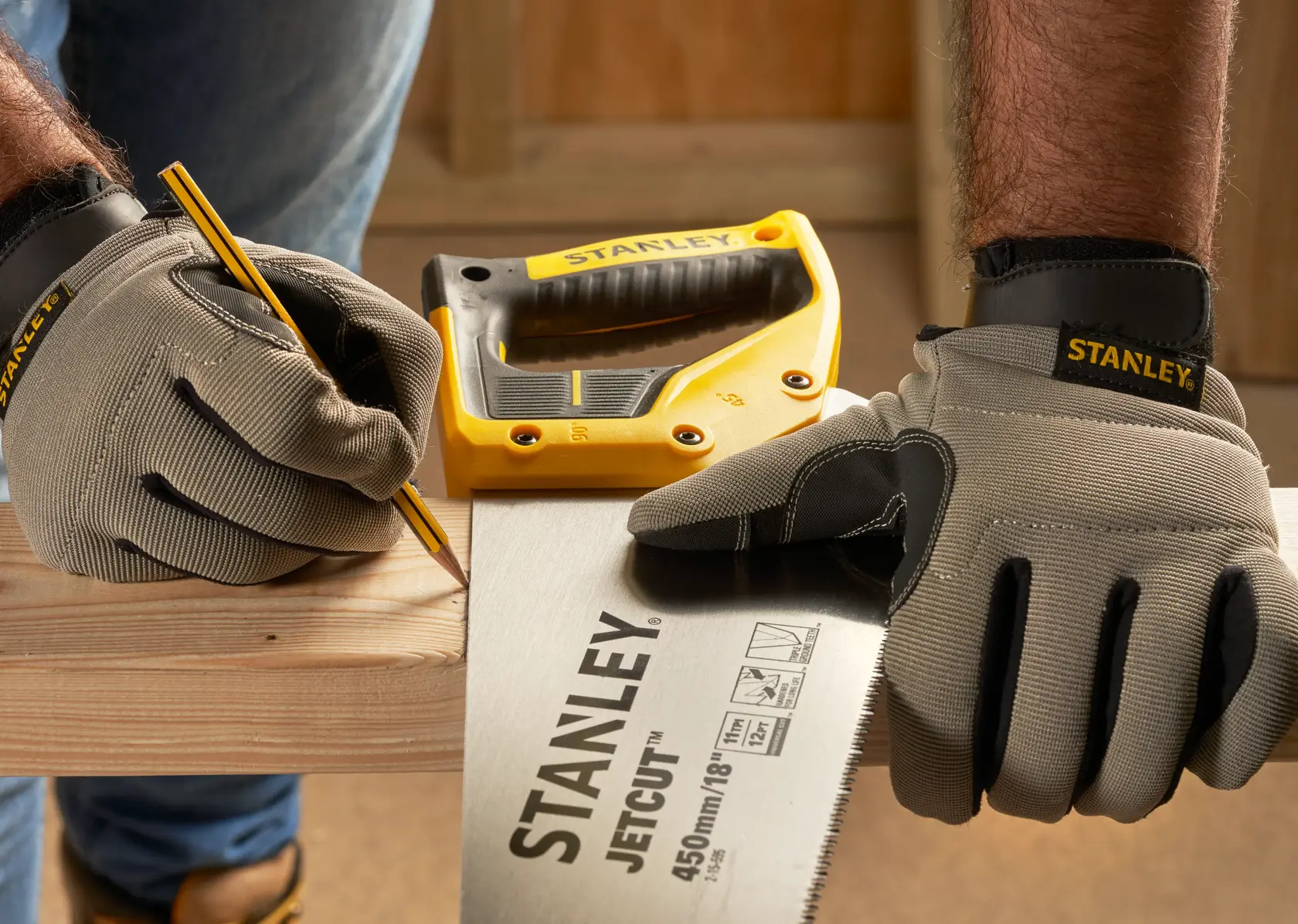 Photo of STANLEY 2-15-595 hand saw and gloves on wood, with a pencil and yellow STANLEY tool in background.