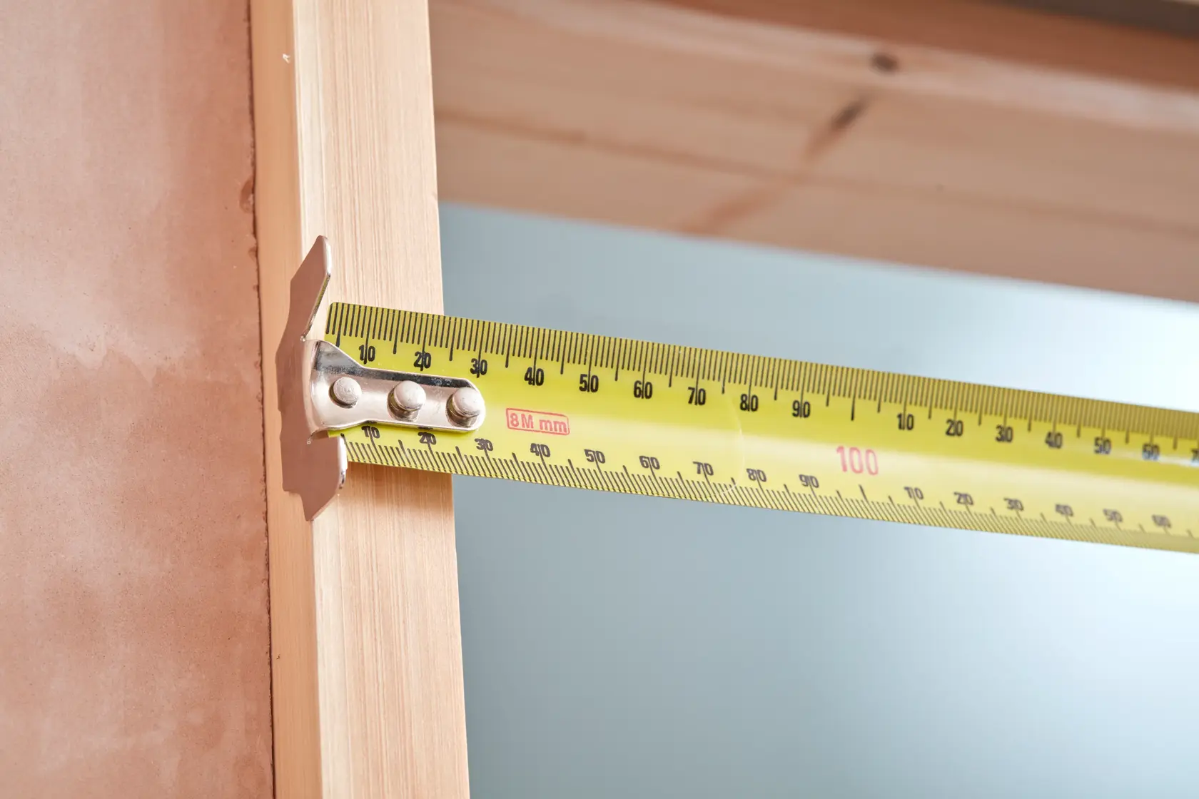 STANLEY 33-894 yellow tape measure extended for measuring wooden frame, product photography side view.