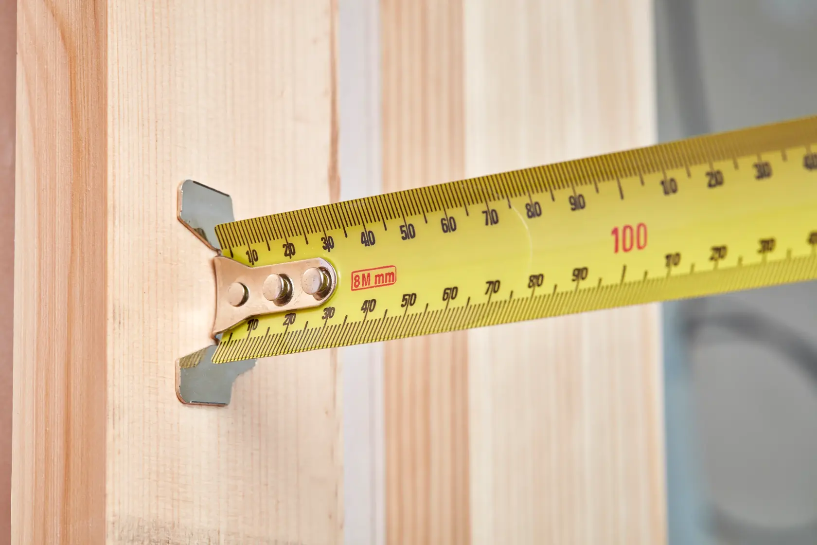STANLEY 33-894 yellow tape measure extended against light wood, close-up side angle.