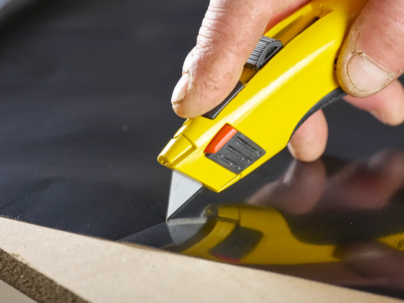 Photo of STANLEY 4-11-921 utility knife cutting black material, close-up view.