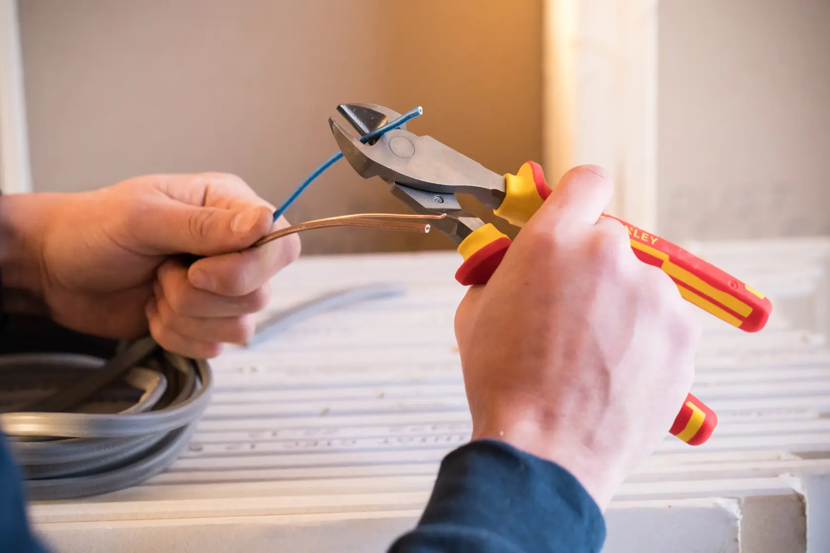 Photo of STANLEY 84-004-S insulated diagonal cutting pliers cutting blue electrical wire.