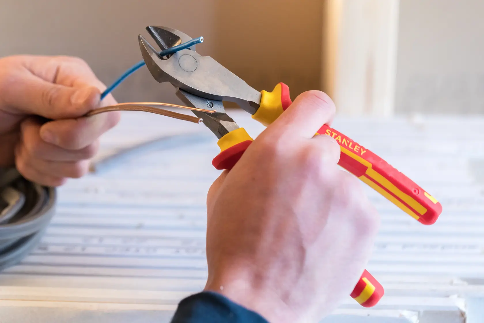 STANLEY 84-004-S insulated wire cutter with red and yellow handle, close-up in use cutting cables.
