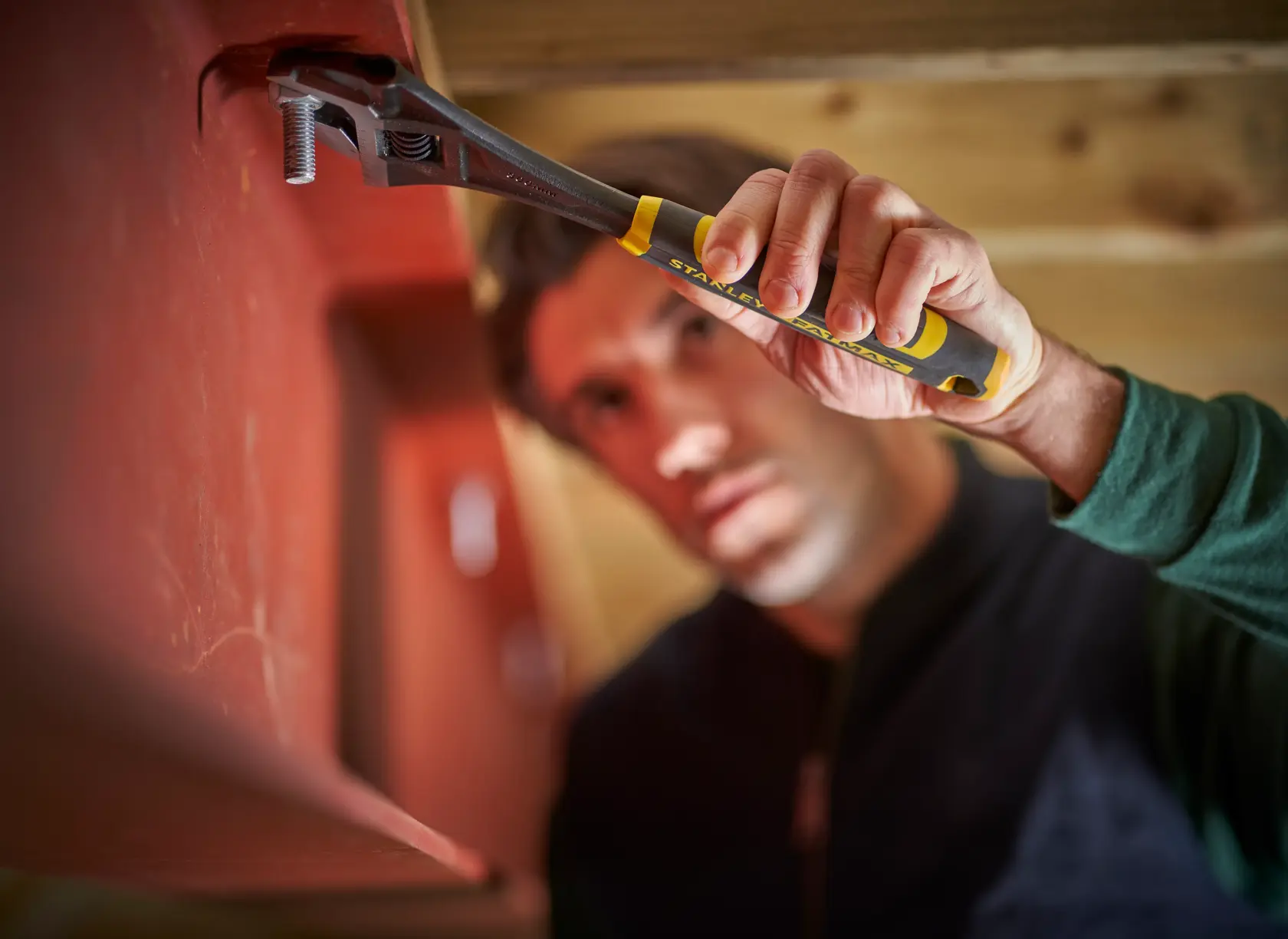 STANLEY FMHT13128-0 adjustable wrench with black and yellow handle tightening bolt, close-up photography.