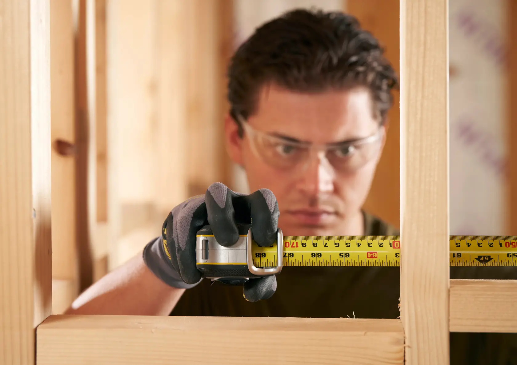 STANLEY FMHT38215-5 tape measure in use for wood framing, close-up view of yellow tape in gloved hand.