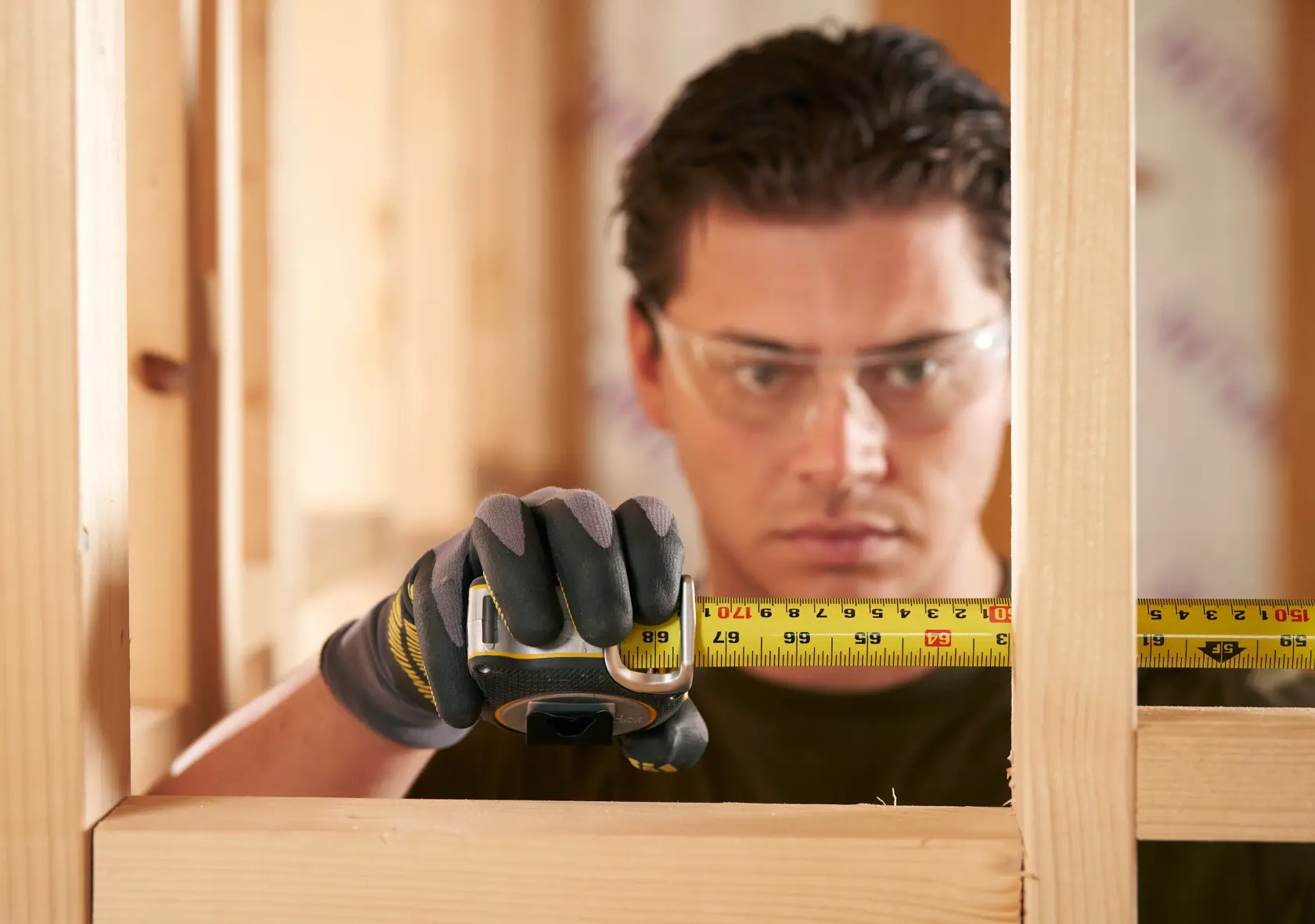 STANLEY FMHT38218-5 tape measure held by gloved hand in construction framing context.