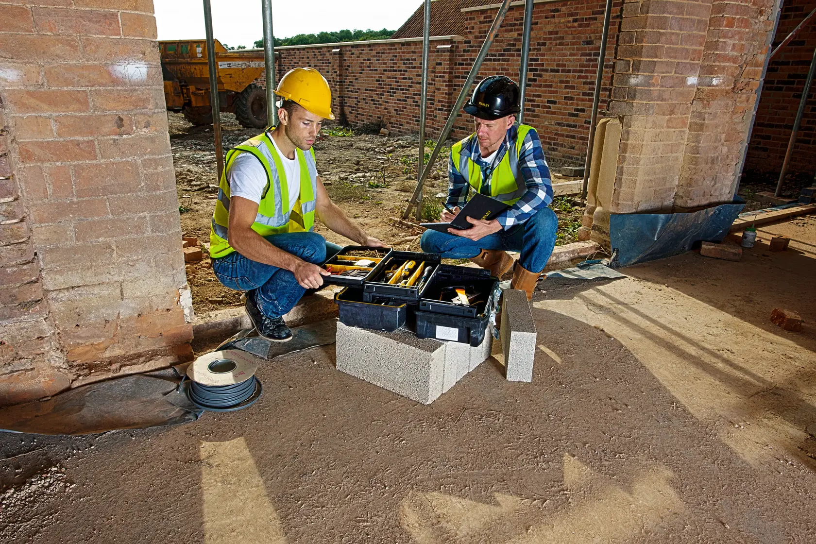 STANLEY FMST1-71219 toolbox in use at construction site, two workers inspecting tools, product photography.
