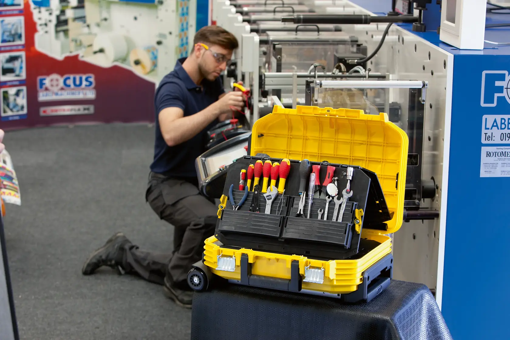 Stanley FMST1-71943 yellow tool box open with hand tools inside, photographed in an industrial workspace.