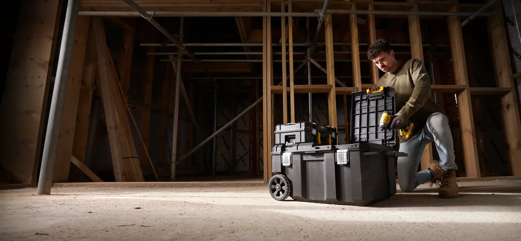 STANLEY FMST17870-1 rolling tool boxes stacked at construction site, front angle, worker kneeling beside.