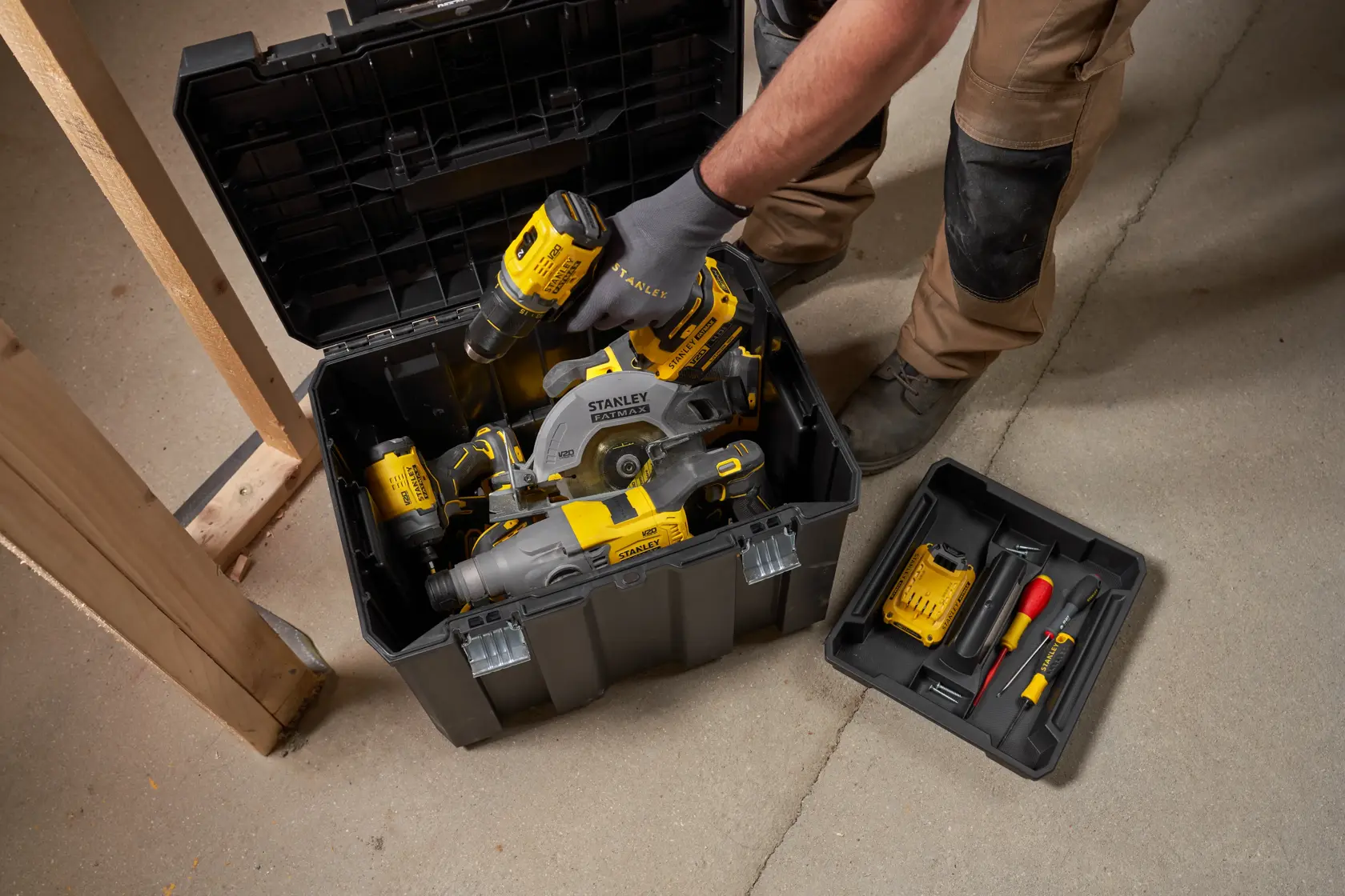 Photo of STANLEY FMST75753-9 storage box with yellow-black power tools and accessories, shown open on a workshop floor.
