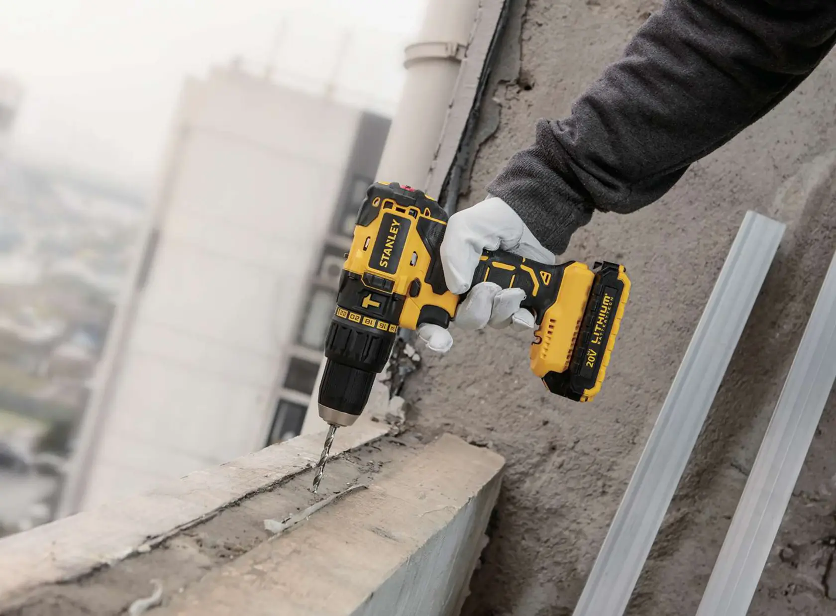Photo of STANLEY SBH20S2K cordless drill in use, drilling into concrete, yellow and black design.