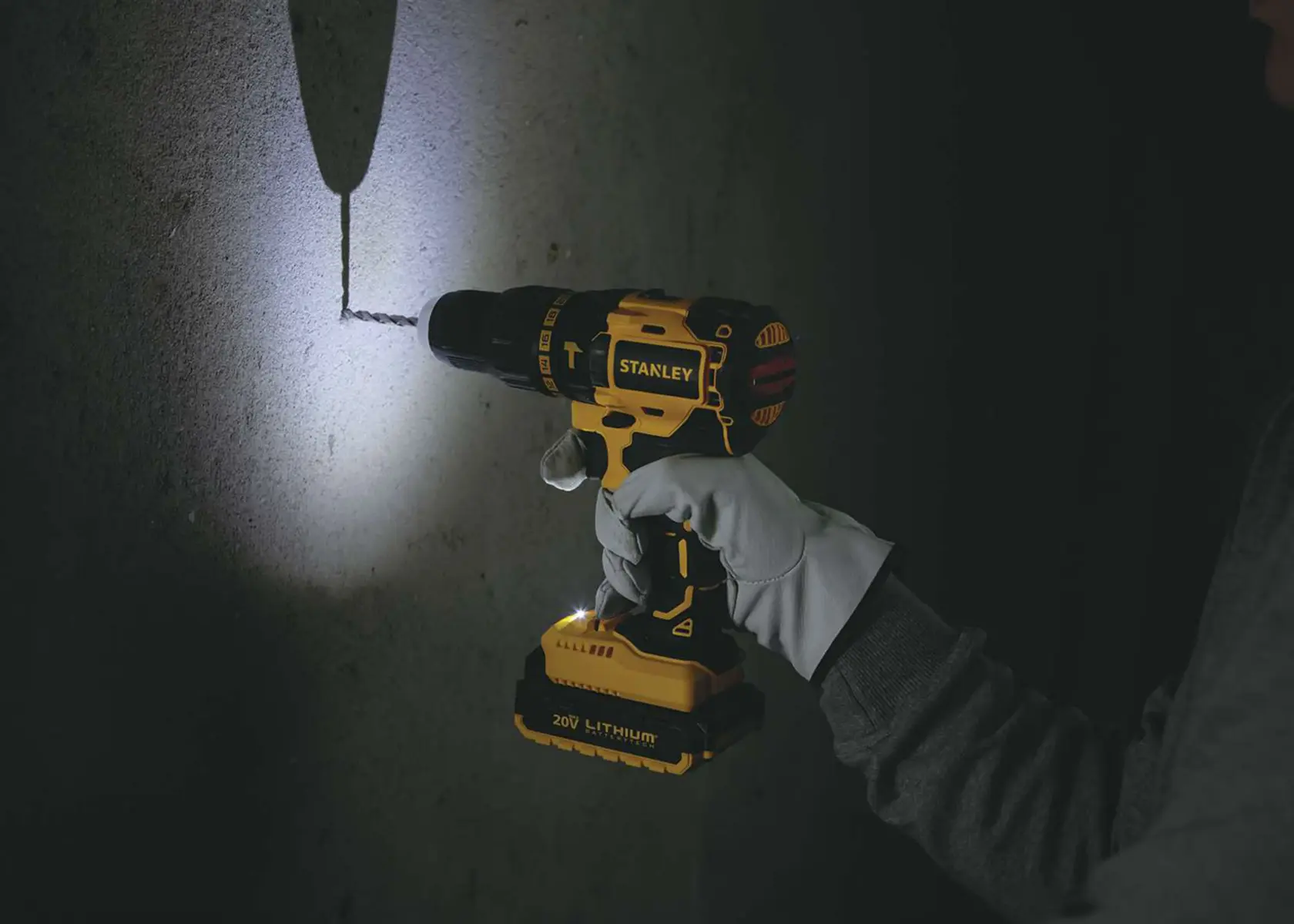 STANLEY SBH20S2K cordless drill in use with LED light, drilling into a concrete wall, close-up.