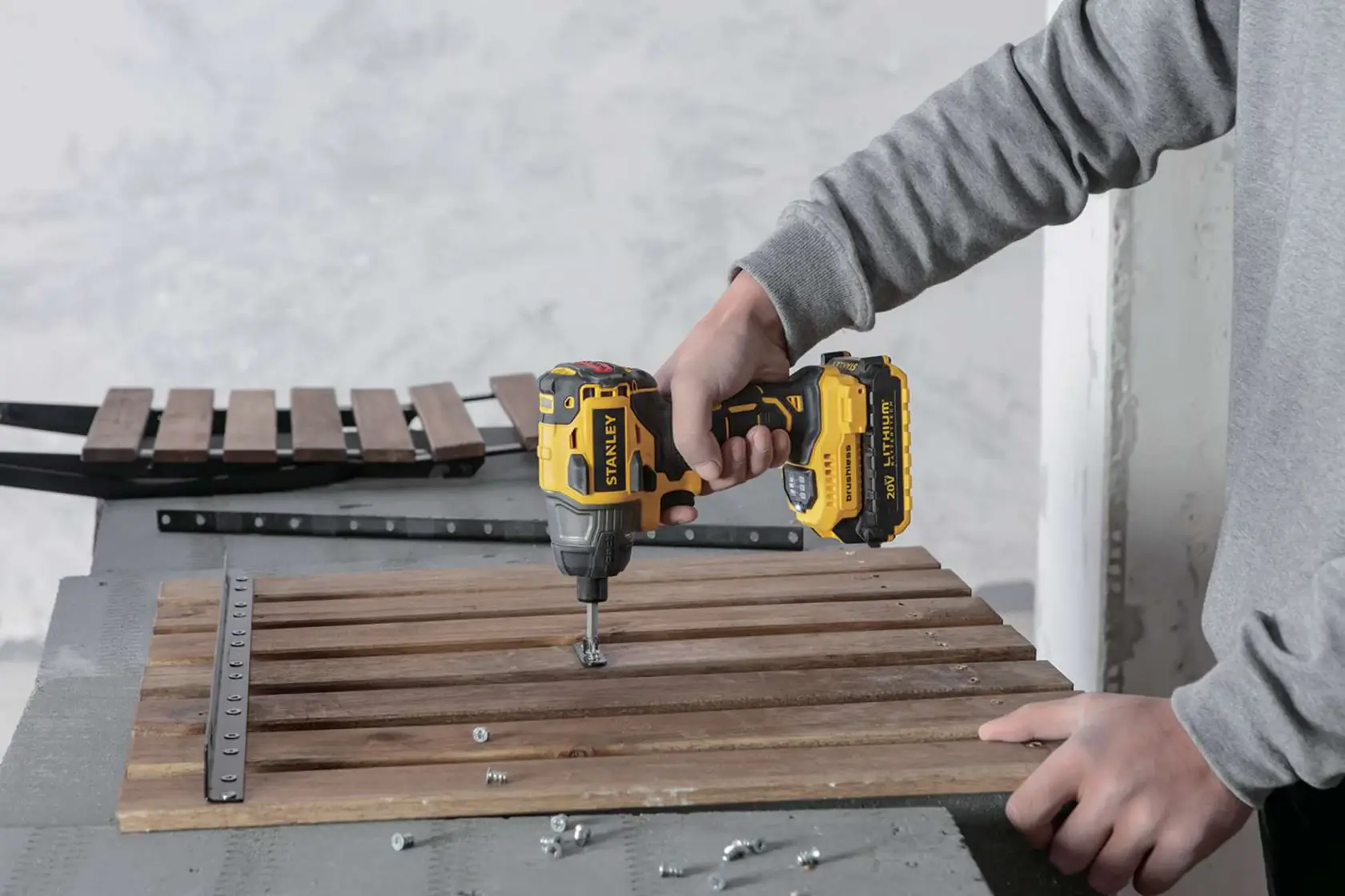 Photo of STANLEY SBI20S2K cordless impact driver being used to drill screws into wooden slats on a table.