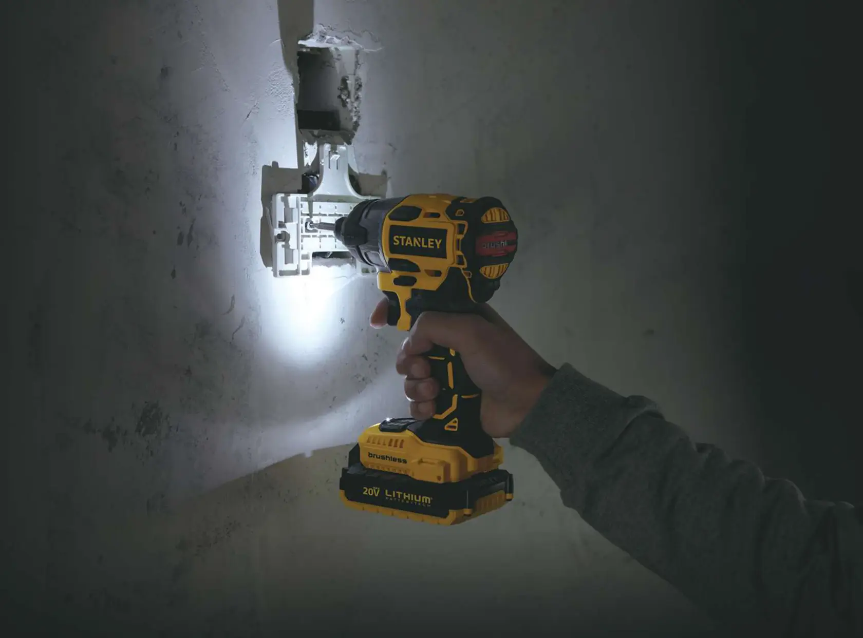 Photo of STANLEY SBI20S2K cordless drill in use, drilling into wall with built-in LED light illuminating work area.