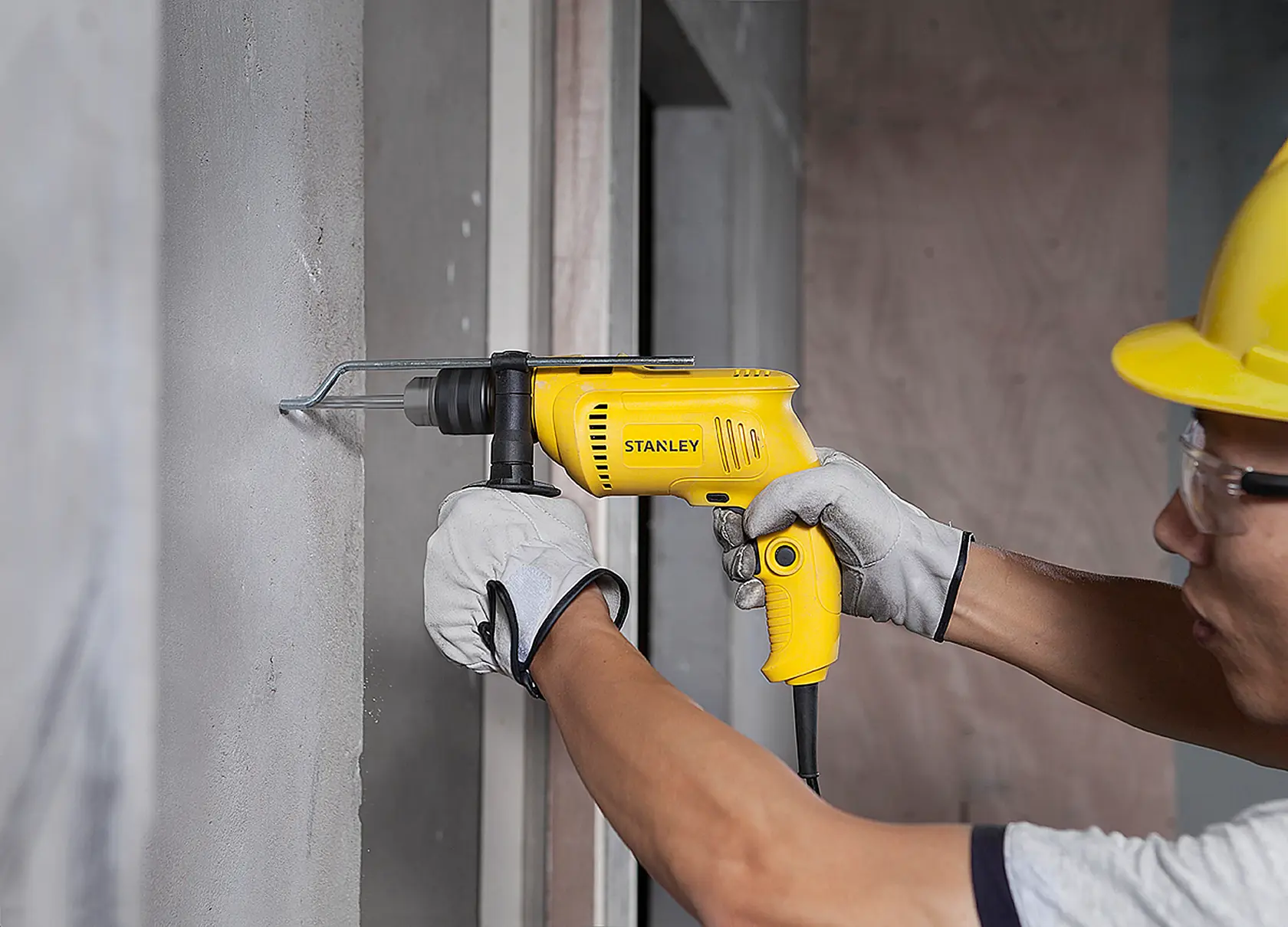 Stanley SDH600 yellow drill in use on concrete wall, close-up side angle, construction scene.