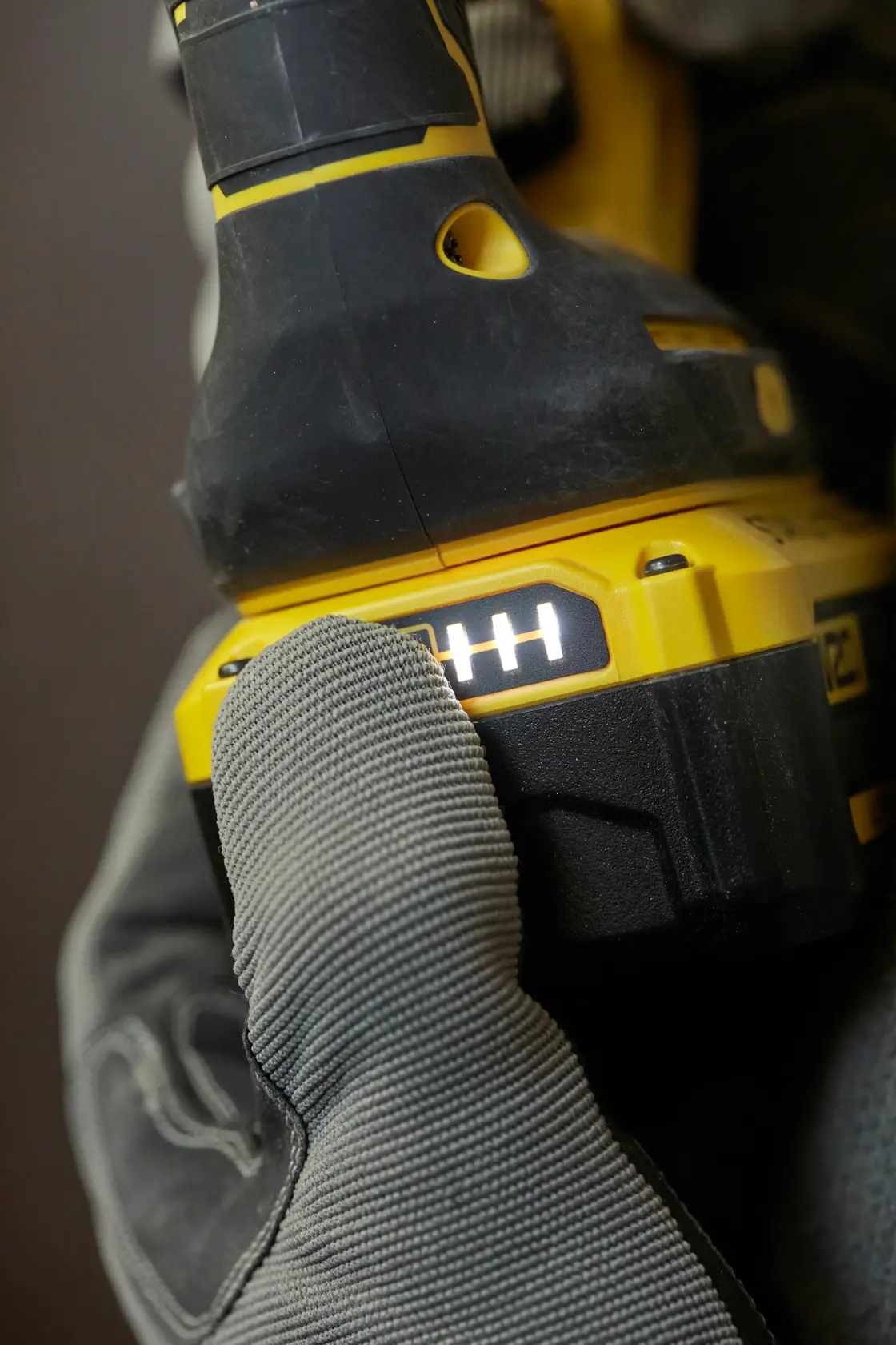 STANLEY SFMCH900M22 cordless drill power indicator close-up held by gloved hand, side angle.