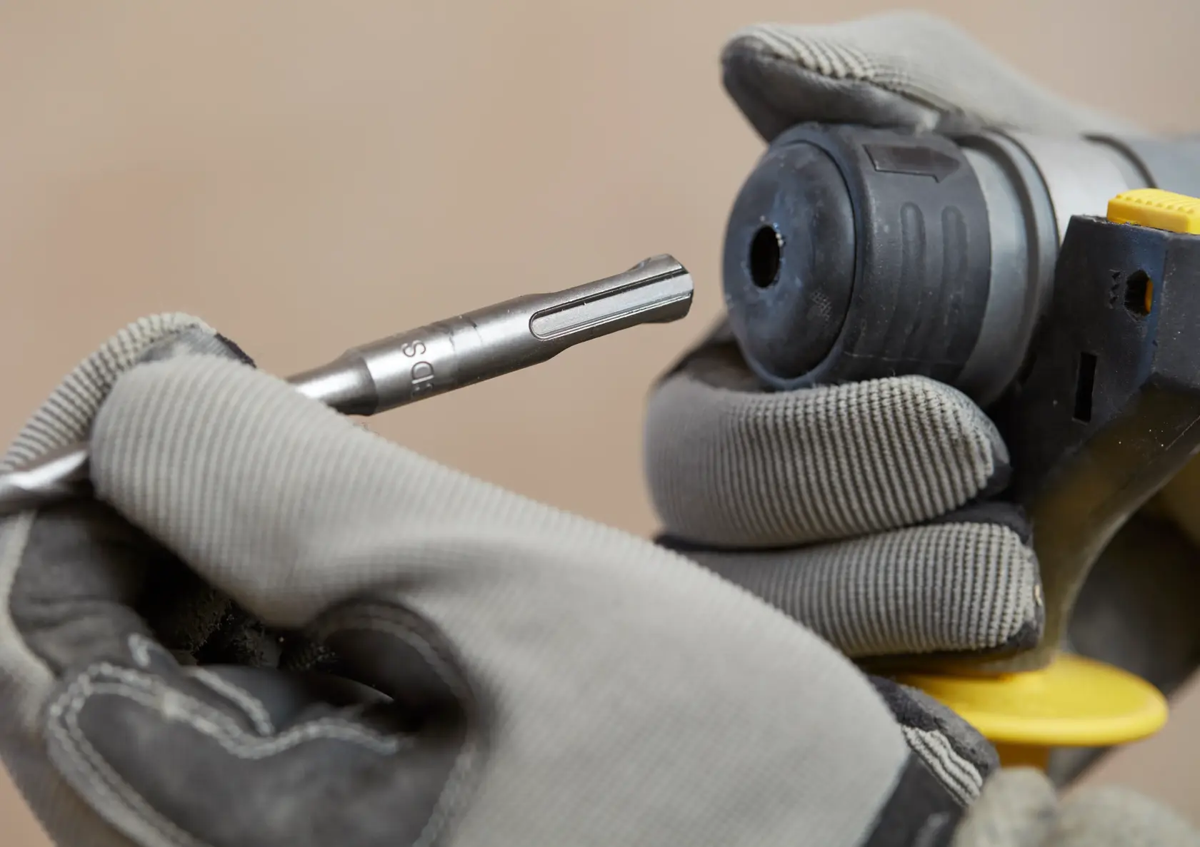 STANLEY SFMCH900M22 rotary hammer close-up with gloved hands inserting a drill bit, product photography.