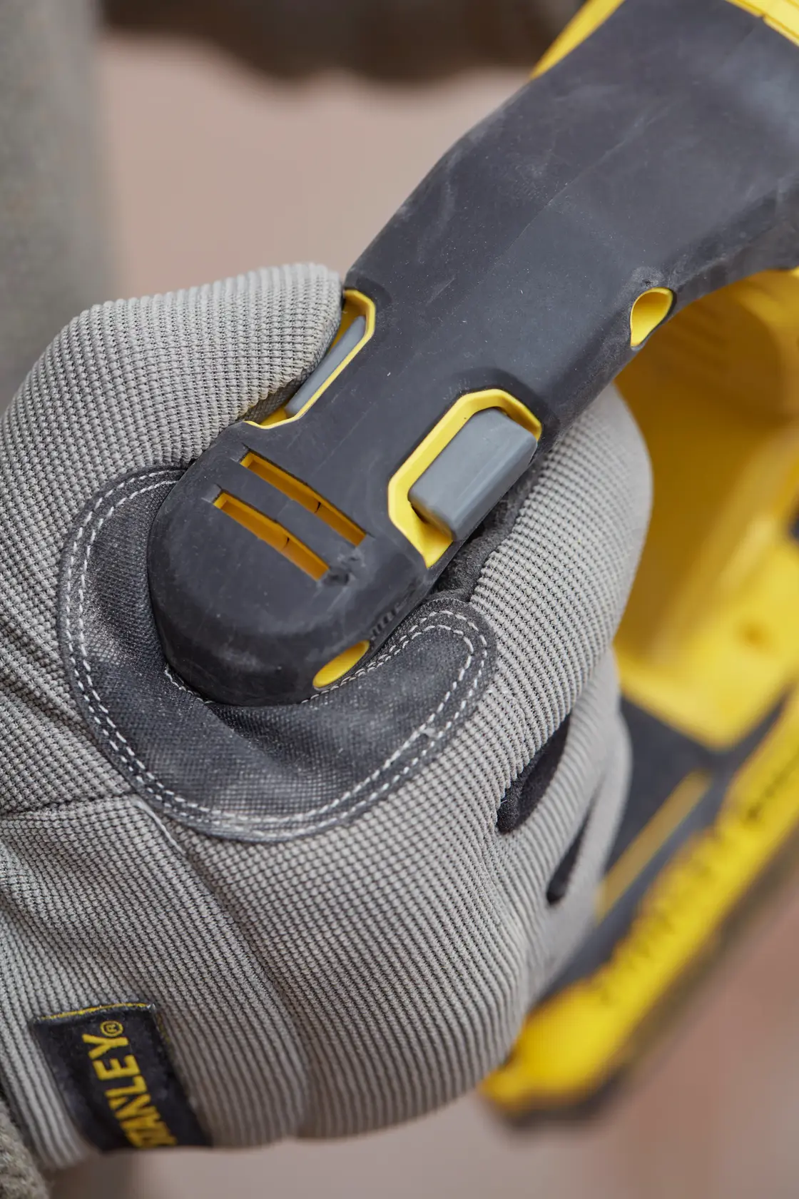 Photo of STANLEY SFMCH900M22 power tool handle with gloved hand gripping, close-up view.