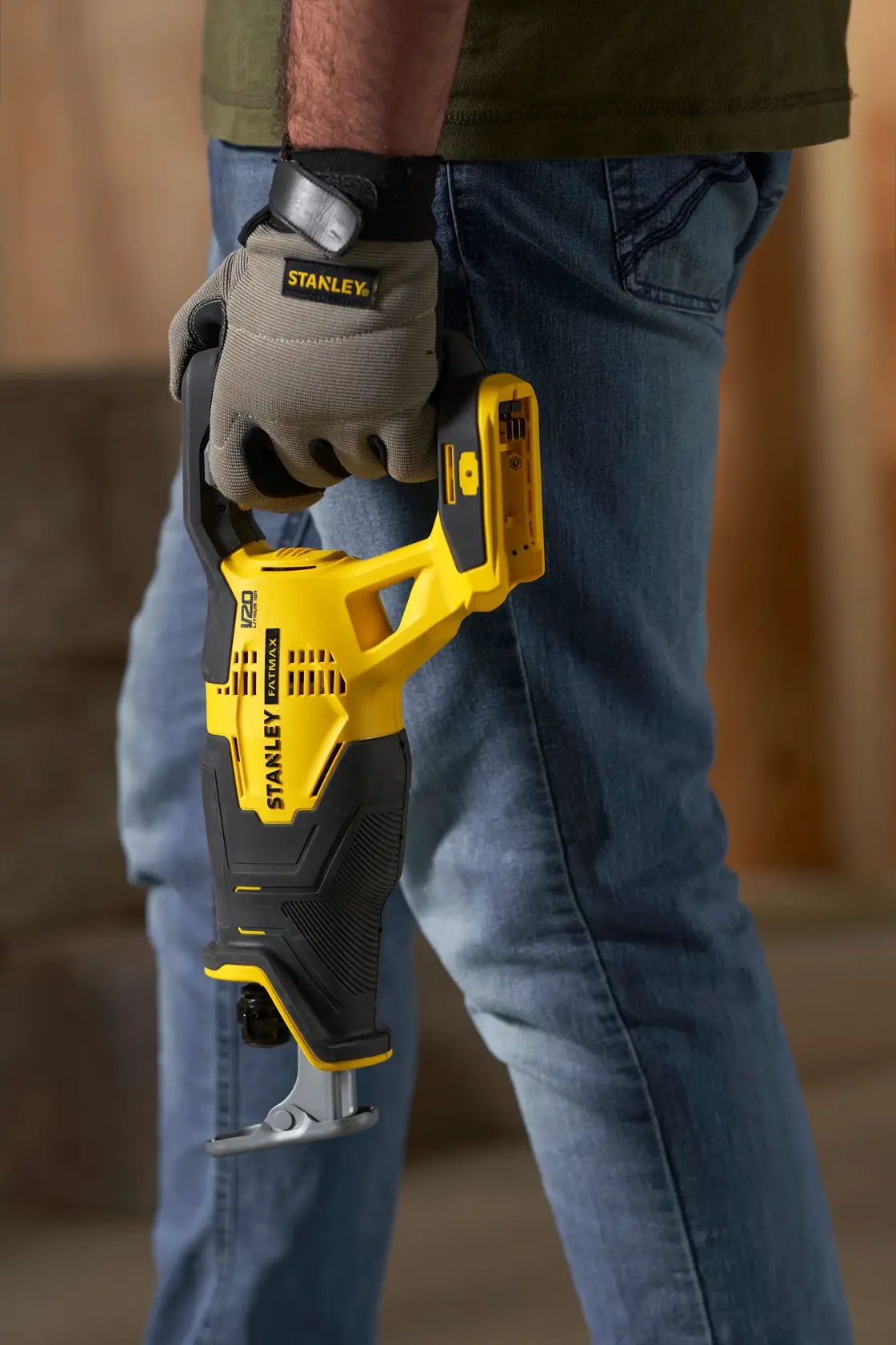 Stanley SFMCS300D1K reciprocating saw held by gloved hand, yellow and black, outdoor context