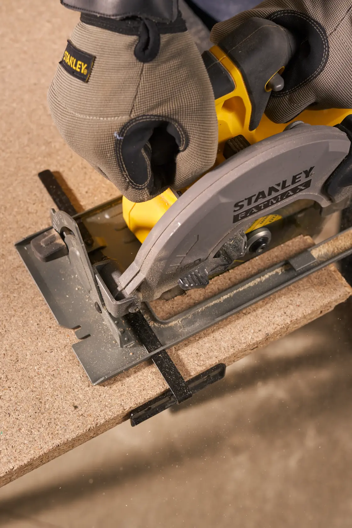 STANLEY SFMCS500D1K circular saw cutting wood, close-up photo showing gloved hands and saw blade.