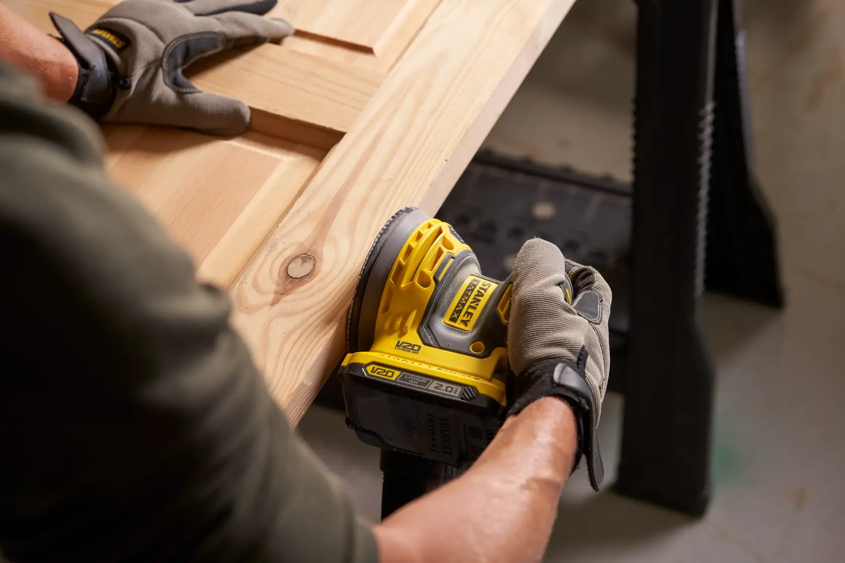 Photo of STANLEY SFMCW220B cordless sander being used on a wooden surface, close-up view.