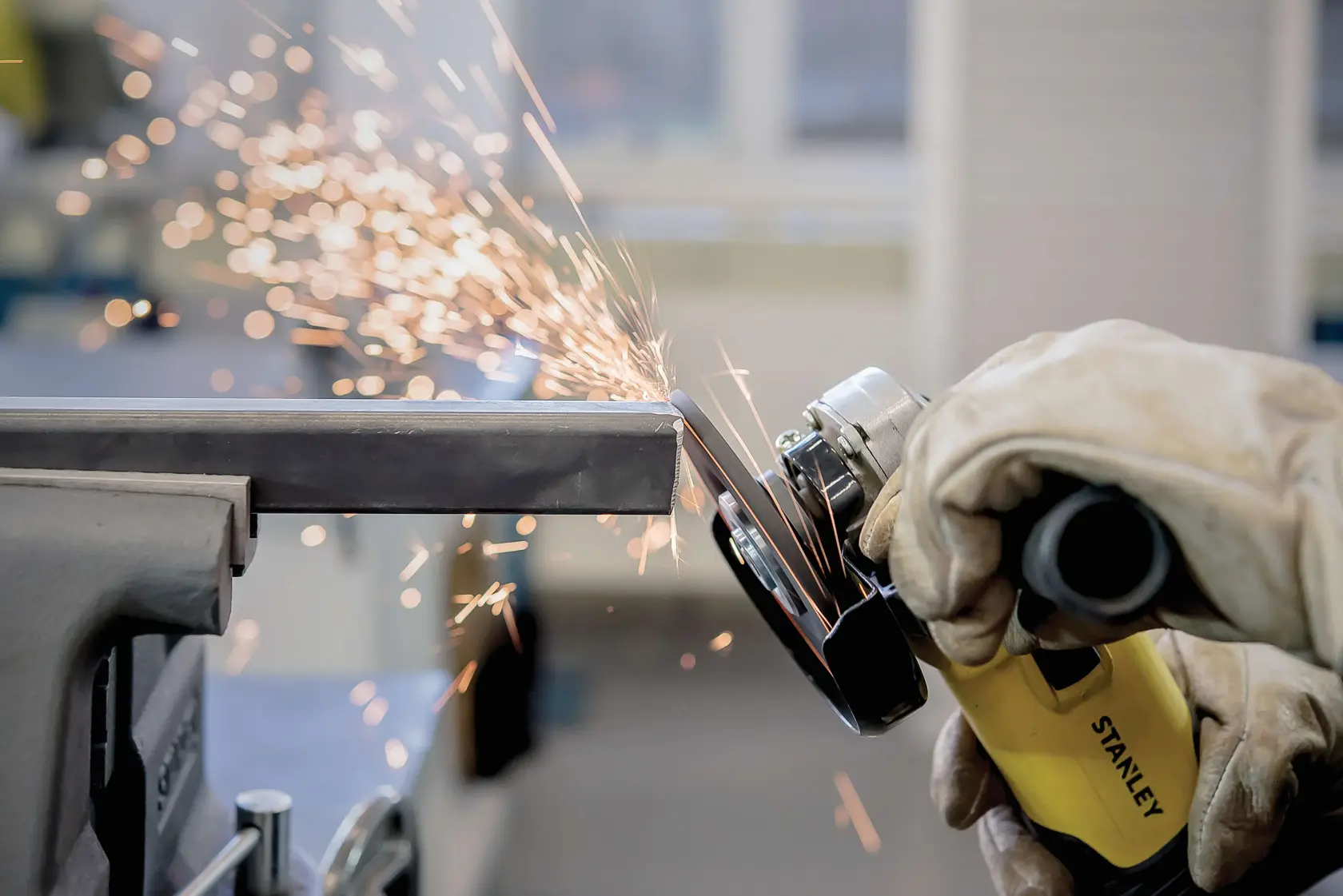 STANLEY STA0413 angle grinder in use, grinding metal with sparks flying, close-up photography.