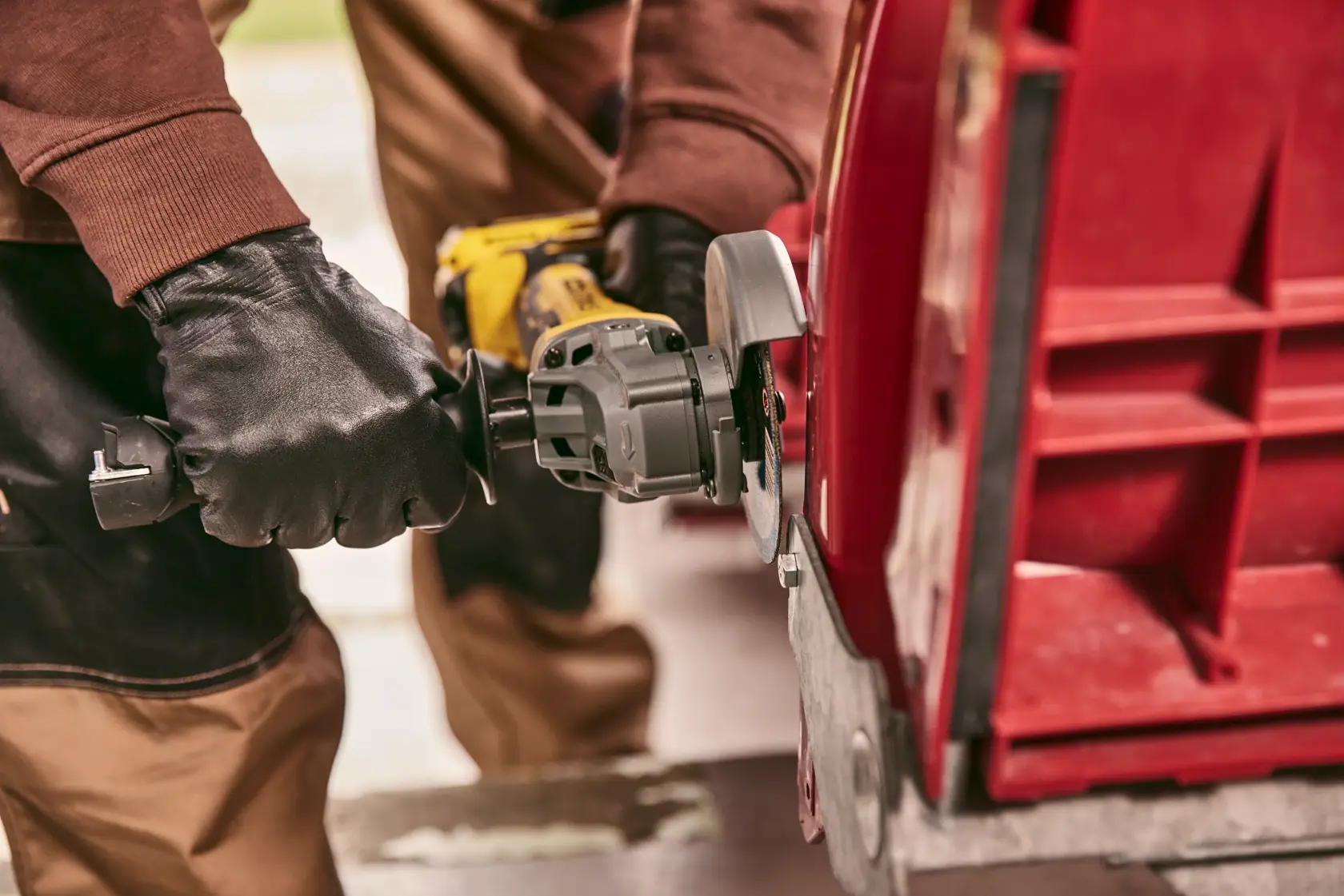 STANLEY STA32637 angle grinder in use cutting red metal, close-up showing gloved hands operating tool.