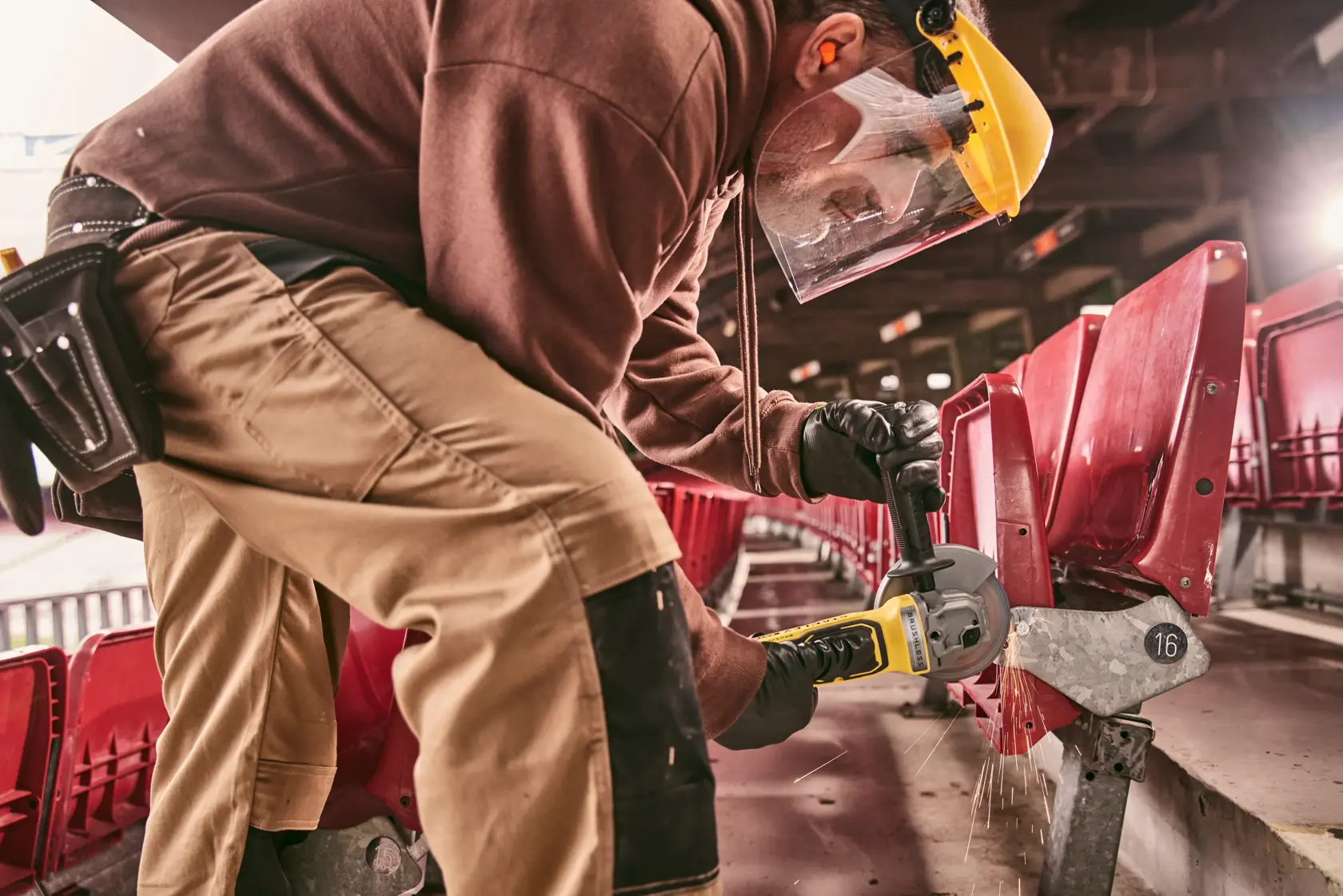 STANLEY STA32637 photography of worker using power tool on stadium seating, wearing protective gear.