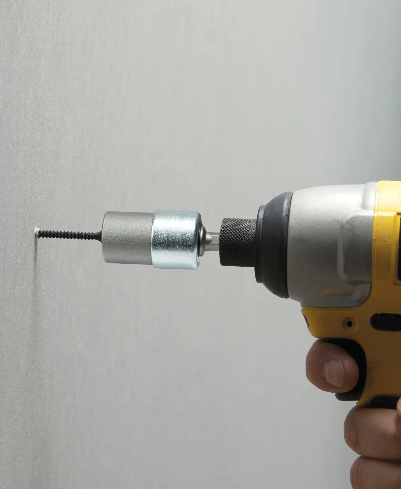 STANLEY STHT0-05926 drywall screw setter attached to drill, side view driving screw into wall.