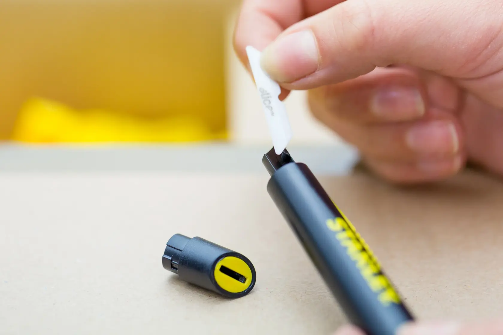 STANLEY STHT0-10293 utility knife, black and yellow handle, blade being inserted, close-up.