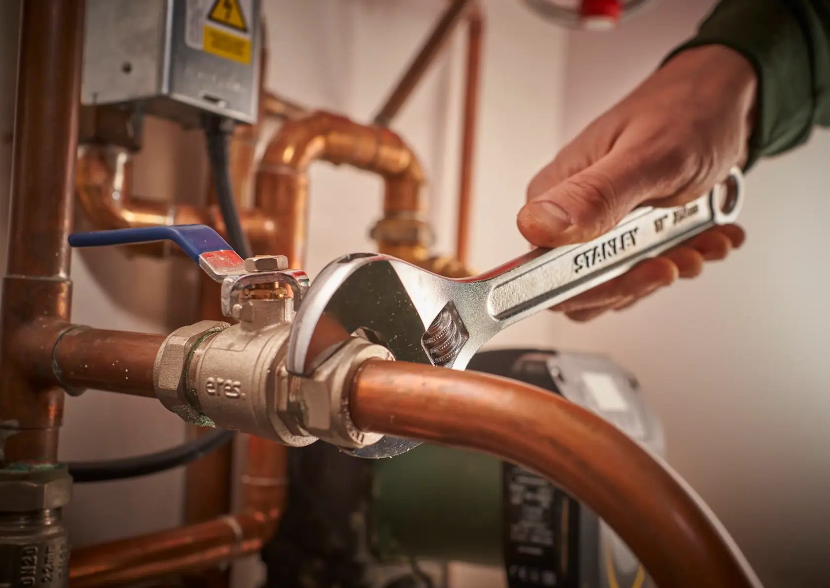 Photo of STANLEY STHT13122-0 adjustable wrench tightening pipe fitting, plumbing context.
