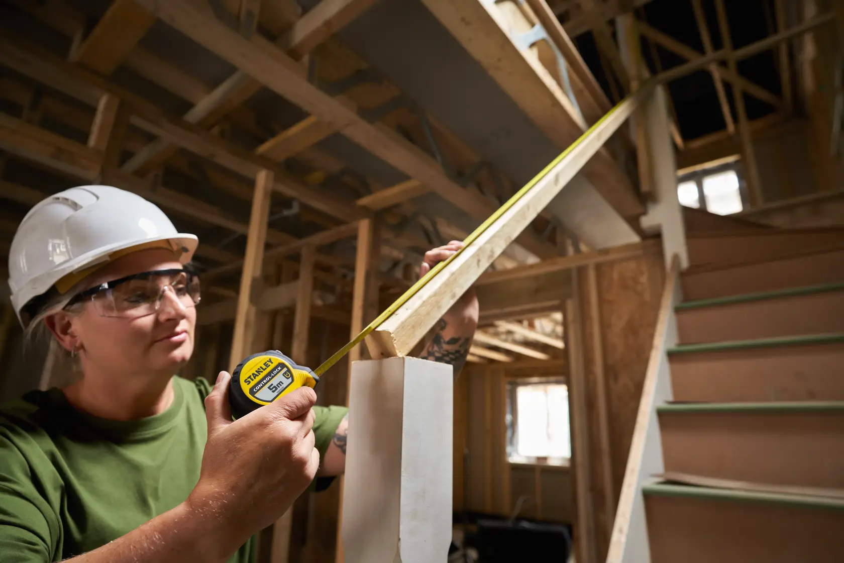 STANLEY STHT37231-0 tape measure used in construction, measuring stair railing, indoor setting.