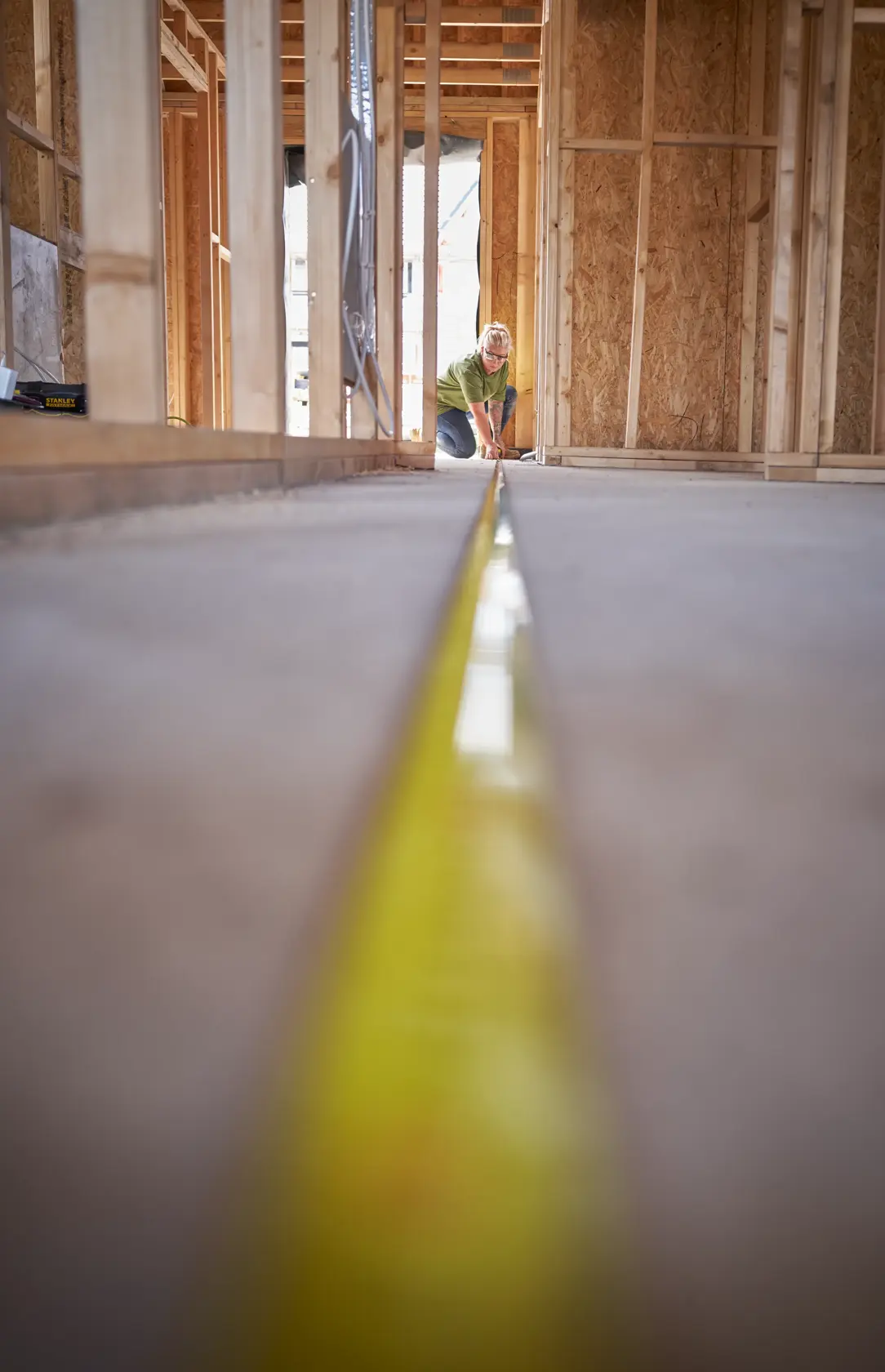 STANLEY STHT37233-0 tape measure extended on concrete floor in unfinished wood framed construction.
